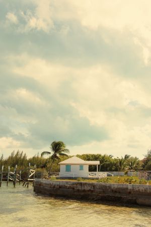 White coastal building on stone pier with palm trees swaying in tropical breeze.