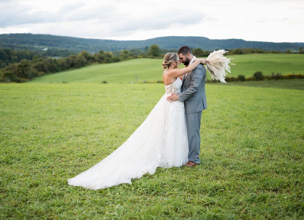 Wedding couple sharing a tender moment on a hilltop meadow with rolling mountains in the background.