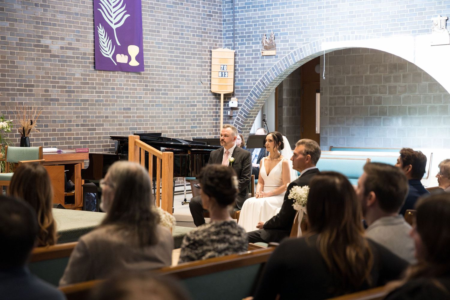 A bright interior scene of a church sanctuary with brick walls and arched architecture during a gathering.