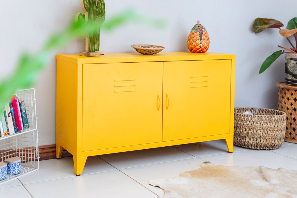 Bright yellow metal locker cabinet with decorative accessories and plants against white wall.