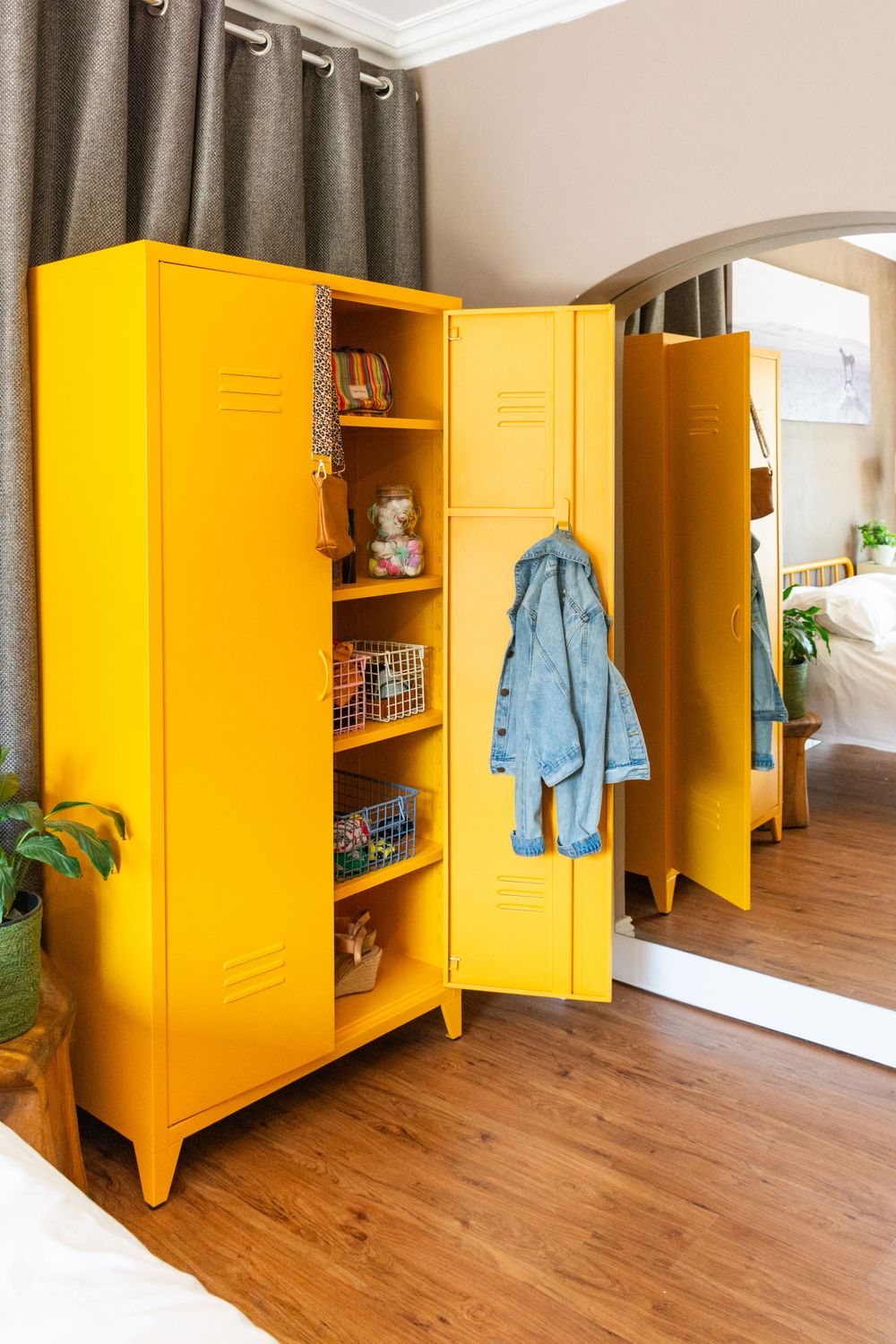 Bright yellow metal storage lockers with open shelving displaying books and a hanging blue jacket.