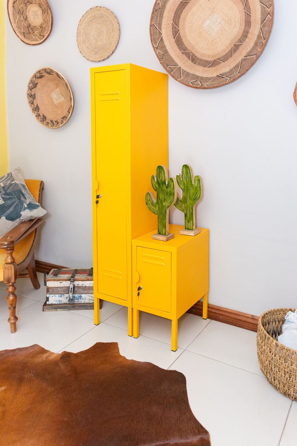 Yellow metal locker cabinet with decorative woven baskets and cactus decor on white floor.