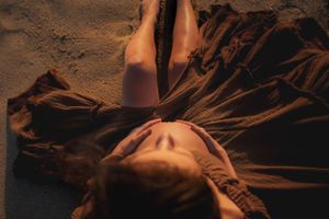 Artistic maternity photo with soft lighting and flowing fabric creating dramatic shadows.