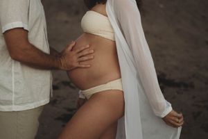 Intimate maternity photo with hands tenderly embracing baby bump.