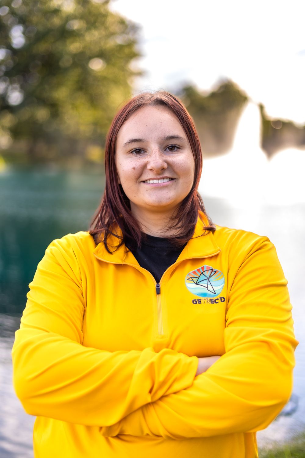 Professional headshot of someone in yellow uniform jacket standing by fountain.