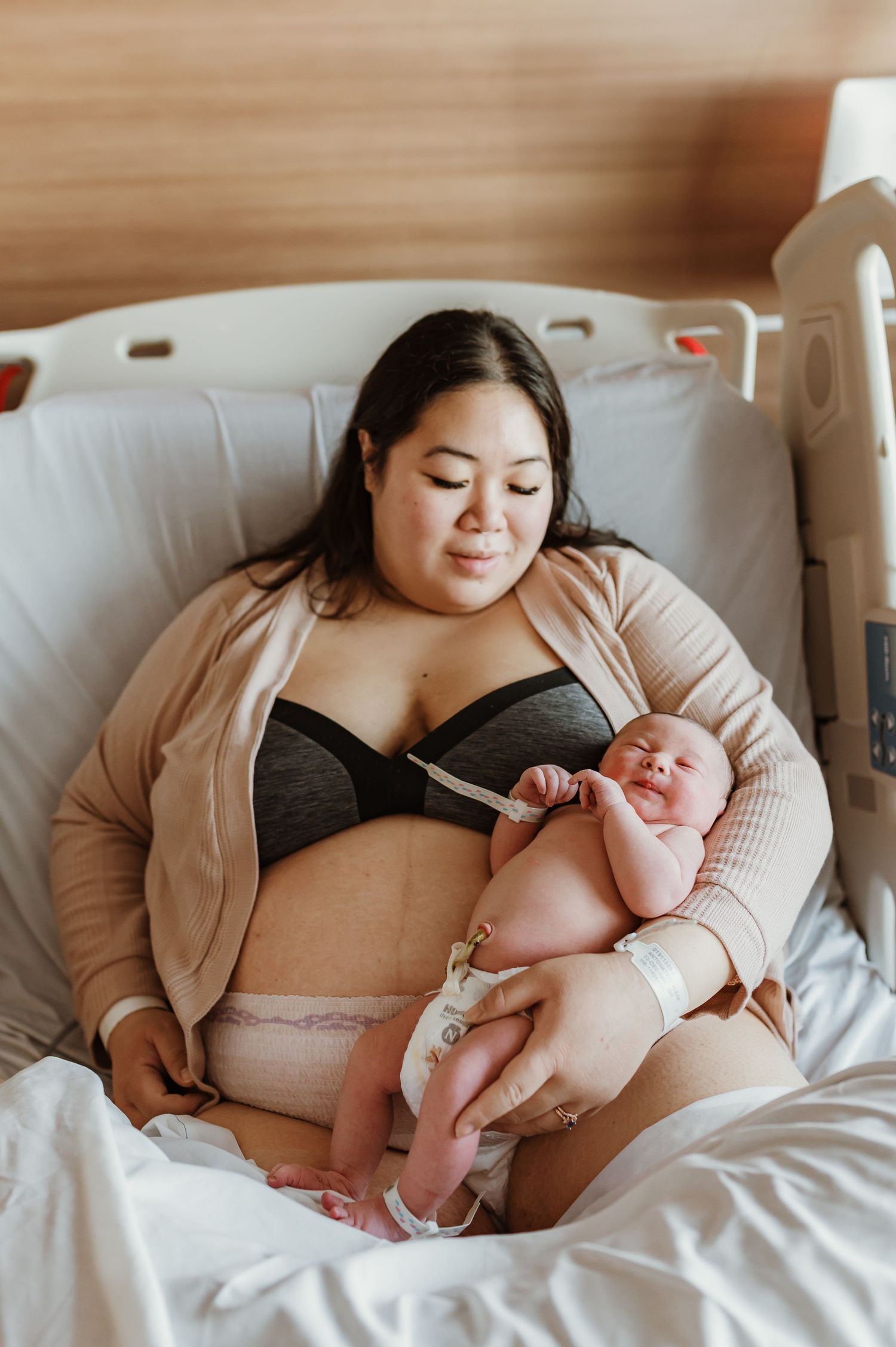 Mother and newborn share tender moment together in hospital recovery room.