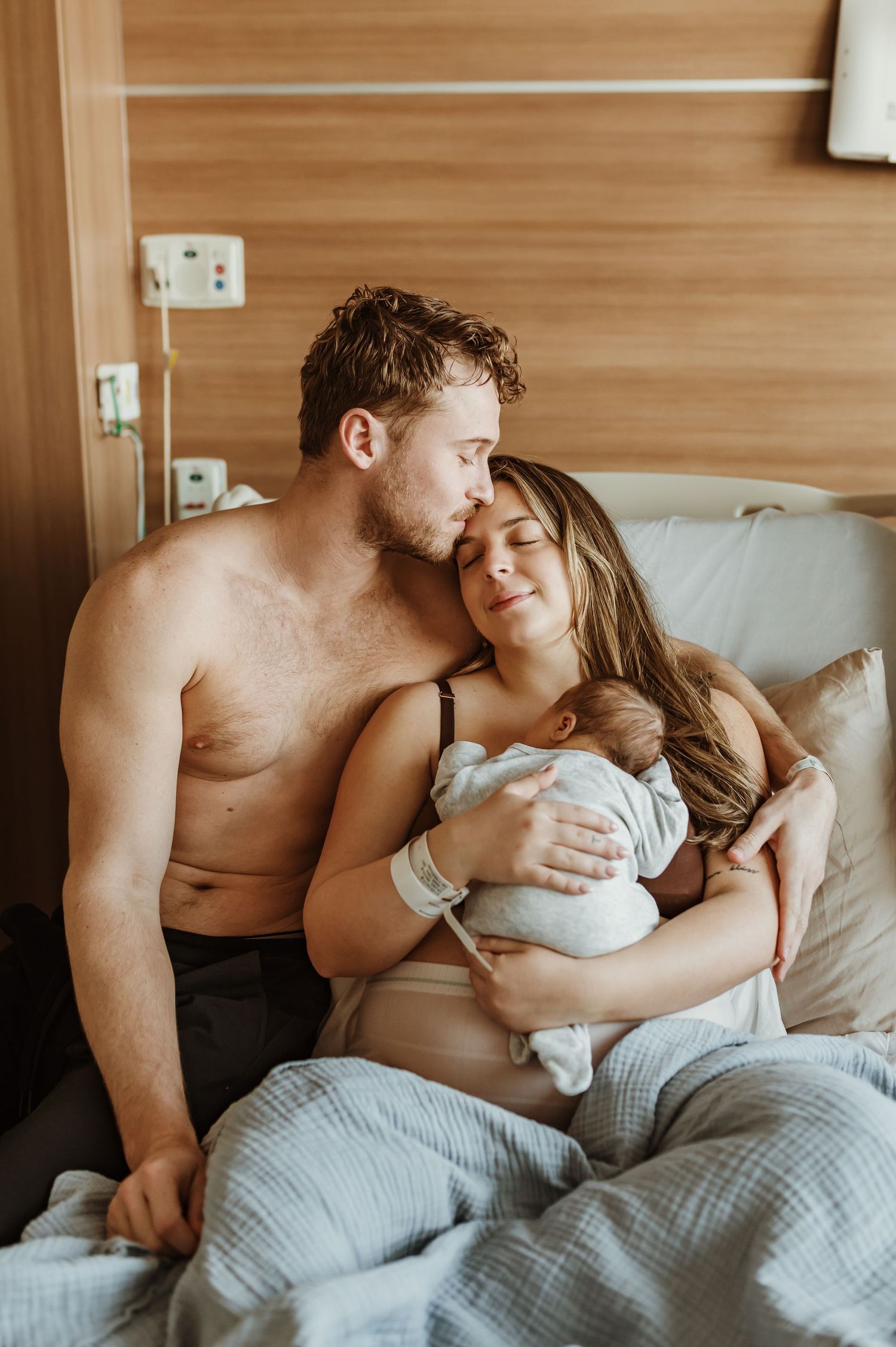 Intimate family moment in hospital room as parents bond with newborn.