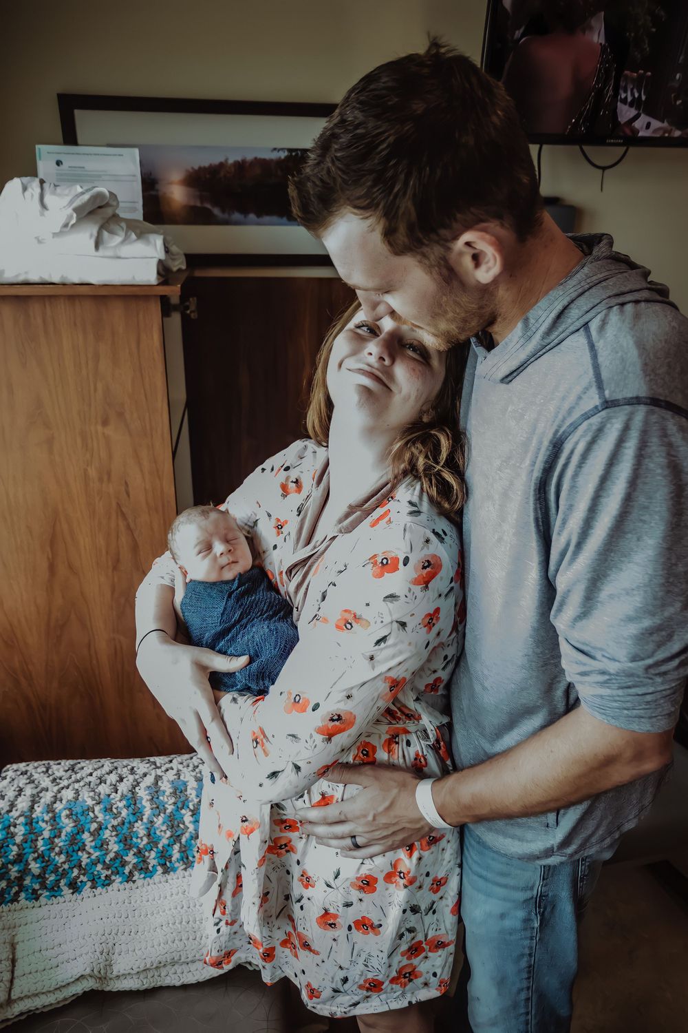 Intimate family moment with newborn baby in hospital room.