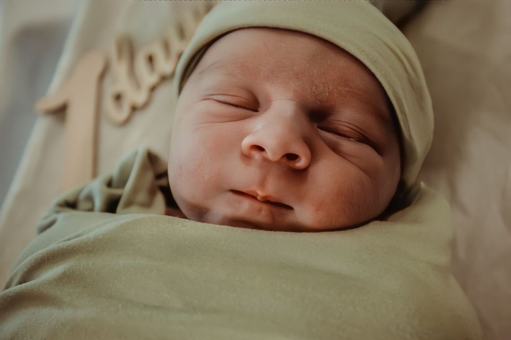 Close up of a peaceful sleeping newborn baby wearing a beige hat.
