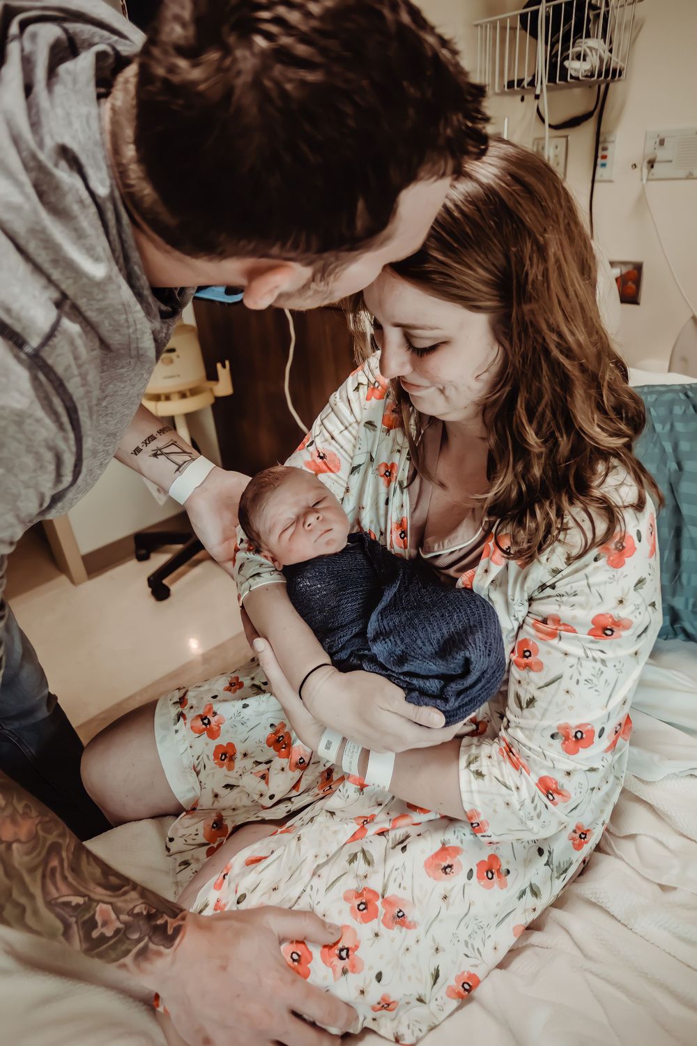Parents looking down adoringly at their newborn baby wrapped in blue.