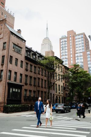 Couple crosses street near Empire State Building in Manhattan's historic brownstone district.