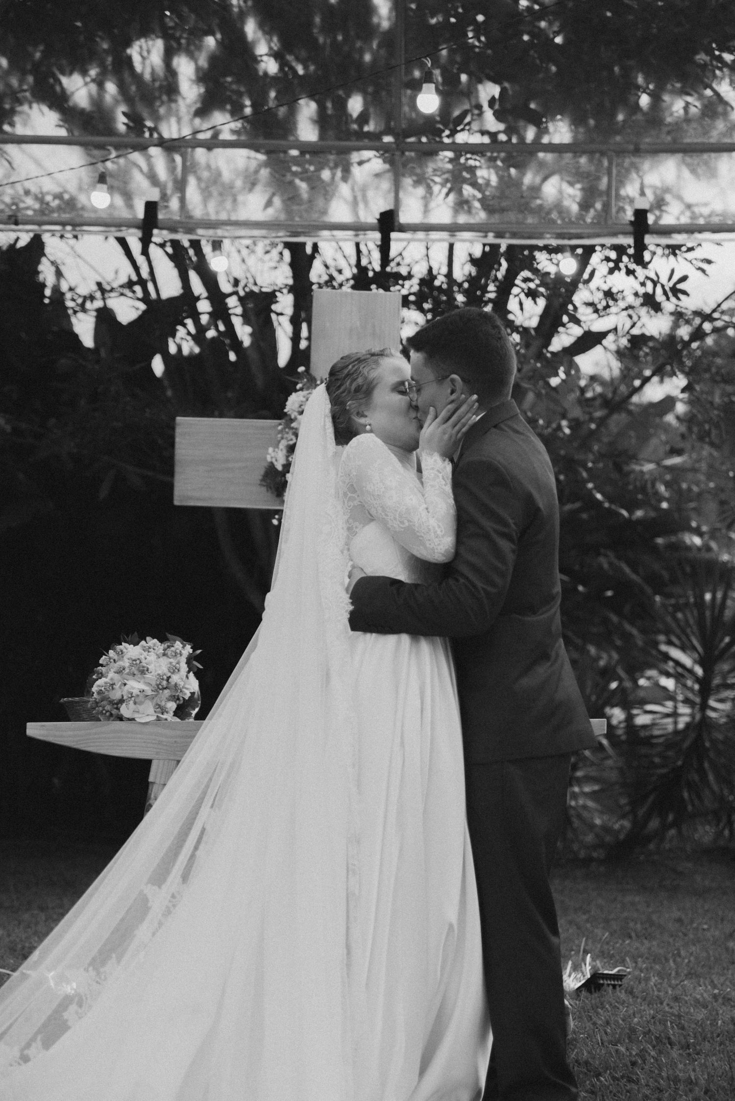 Black and white wedding photo showing a tender moment between newlyweds during their garden ceremony.