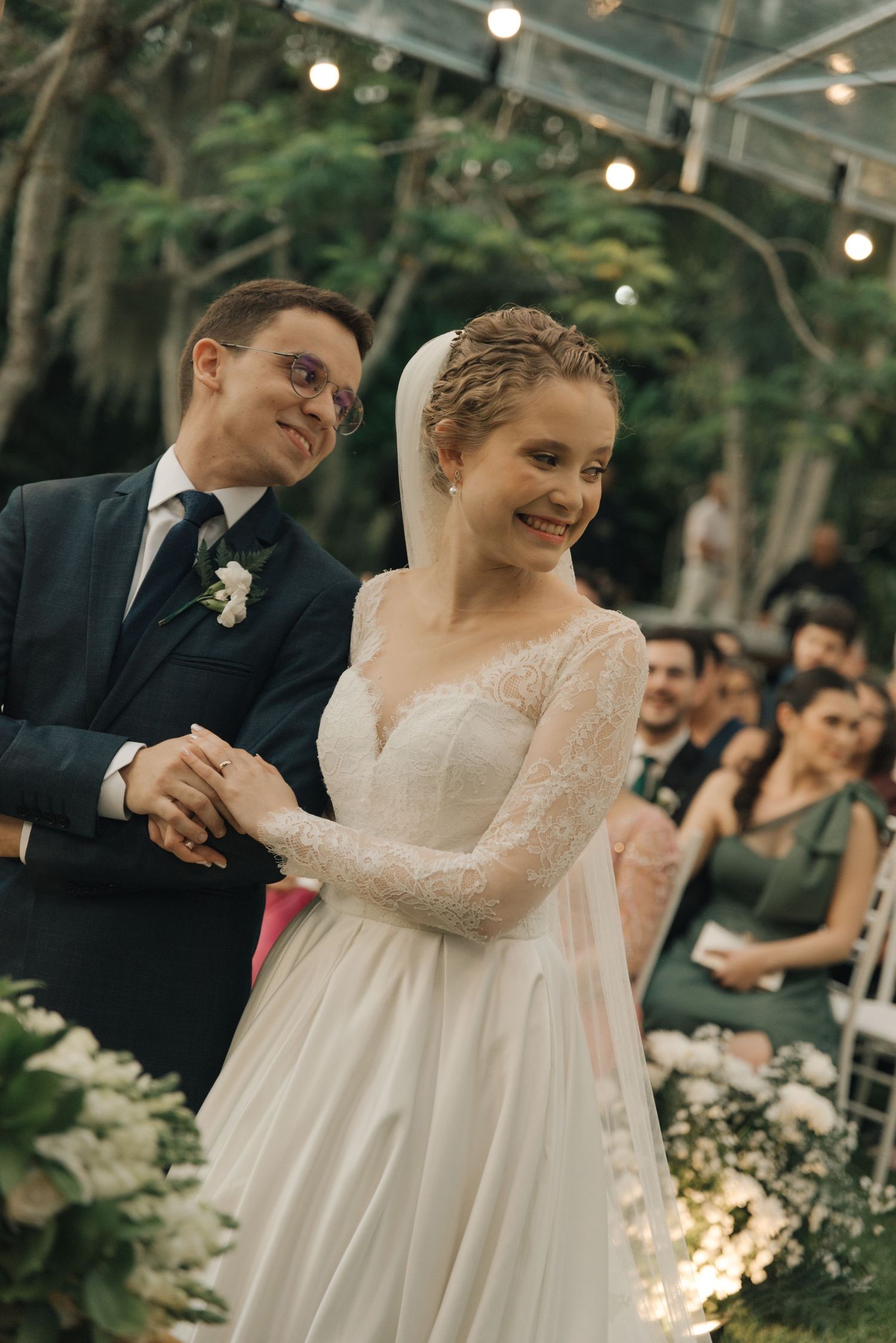 Joyful moment during outdoor wedding ceremony with string lights and garden backdrop.