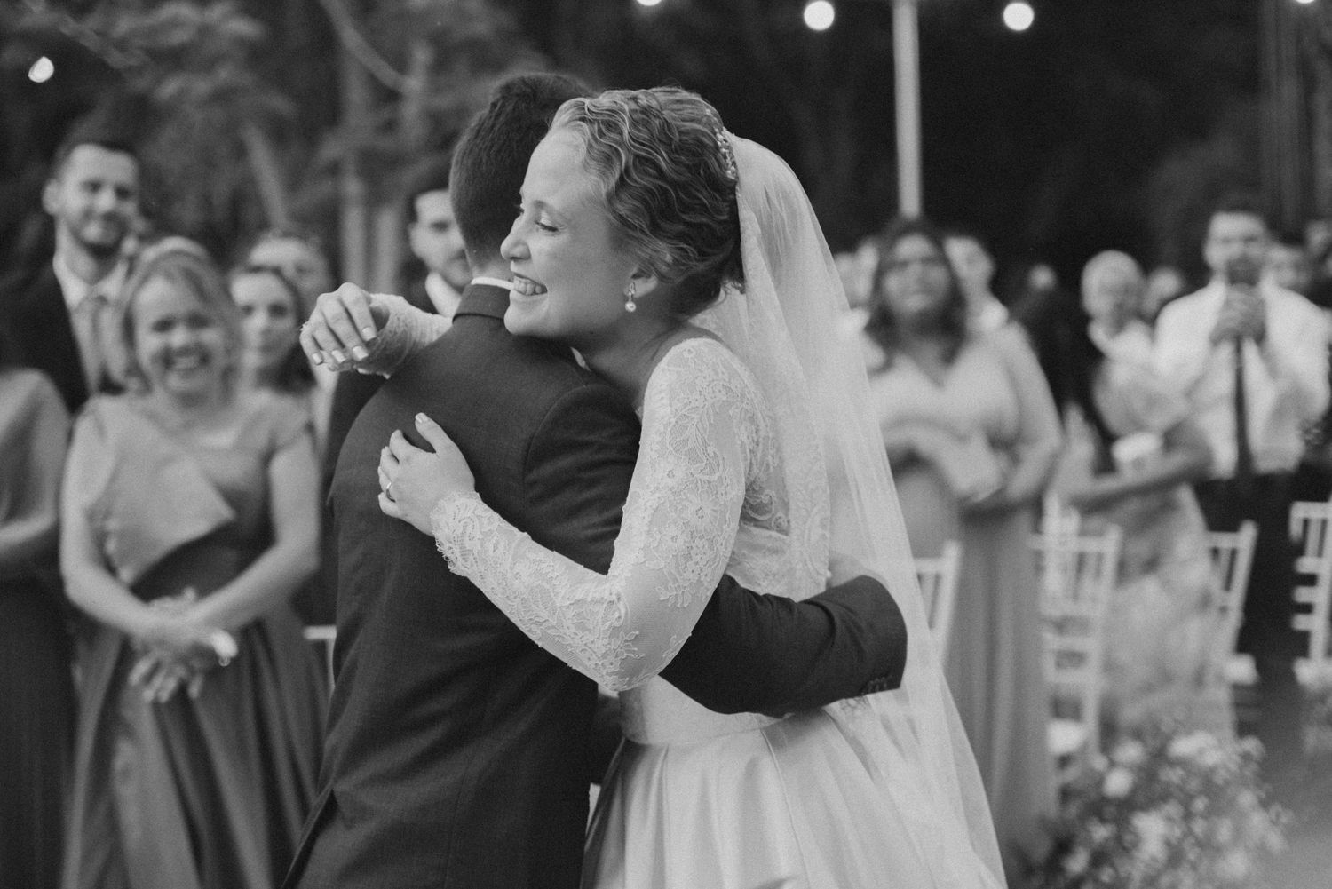 Black and white candid moment of celebration during outdoor wedding ceremony.