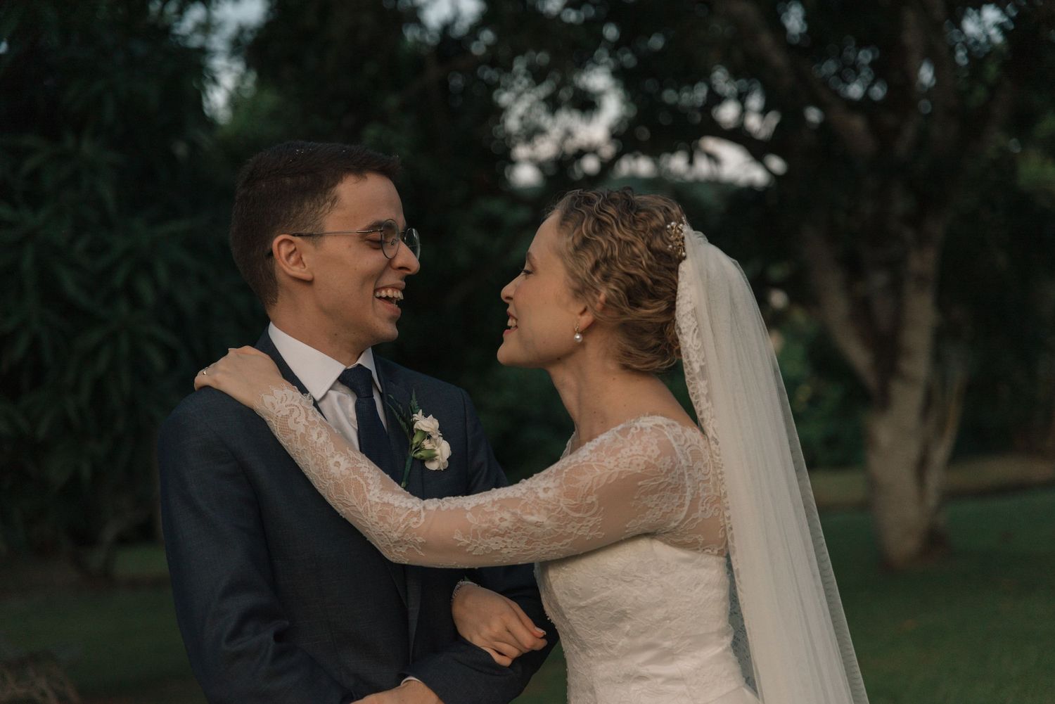 Wedding couple in tender moment with lace dress details and navy suit.