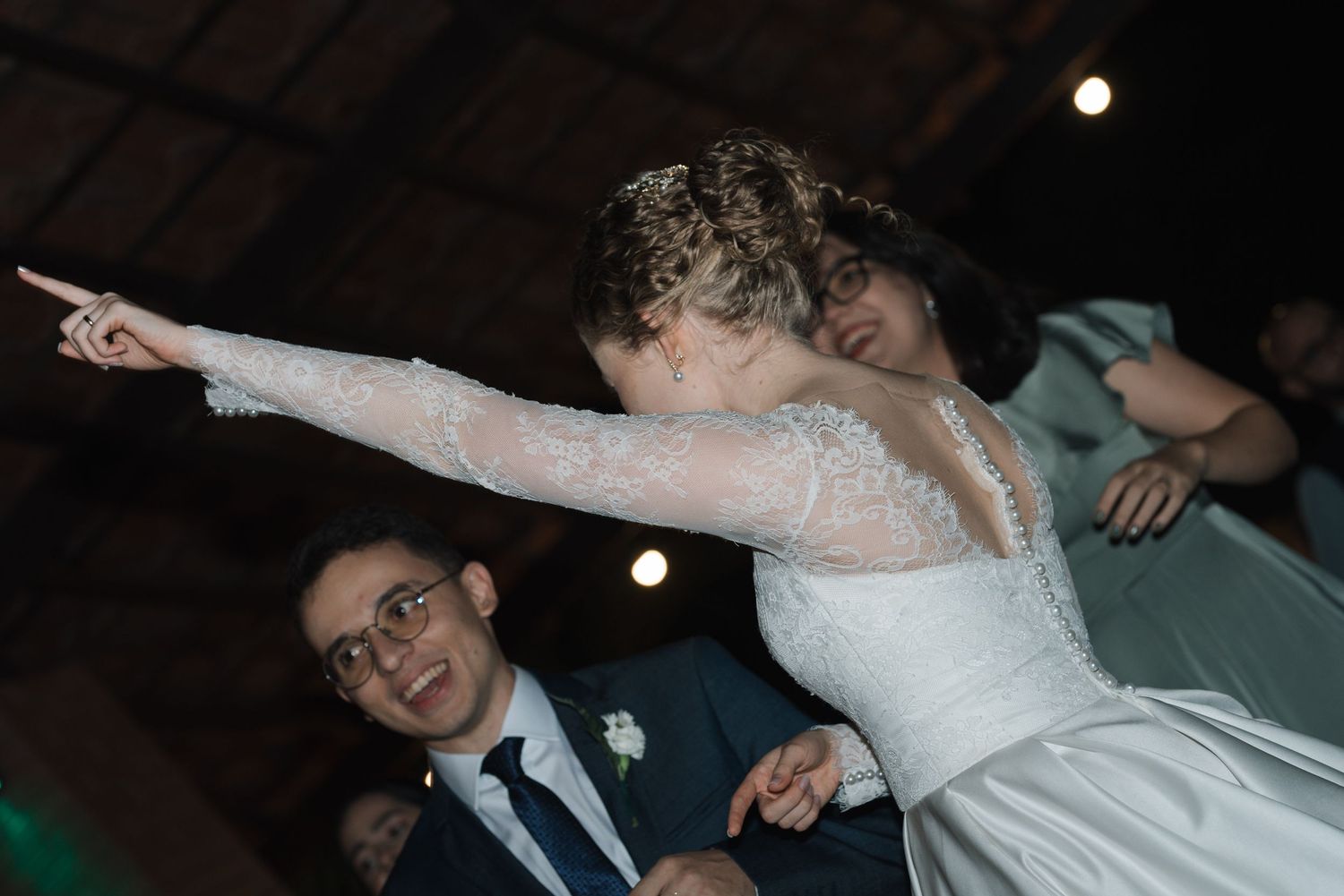 An energetic dance moment captured at a wedding reception with dramatic lighting effects.