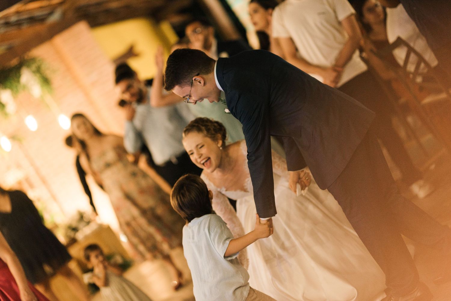 A romantic first dance moment at a dim-lit wedding reception with warm glowing lights.
