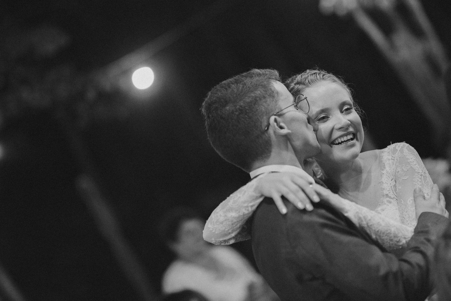 Black and white candid moment of couple dancing at nighttime wedding reception.