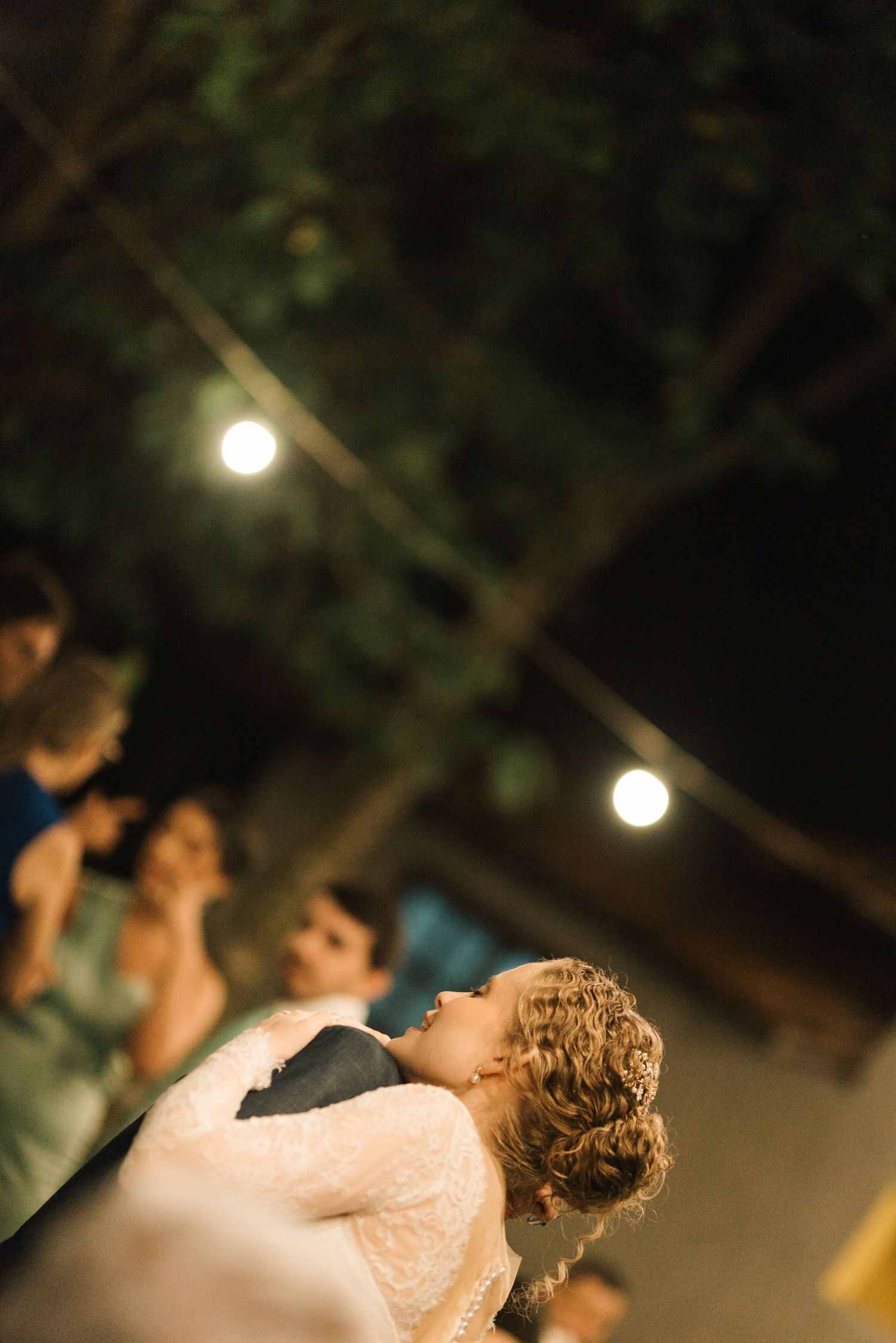 Romantic dance dip under string lights at outdoor evening reception.
