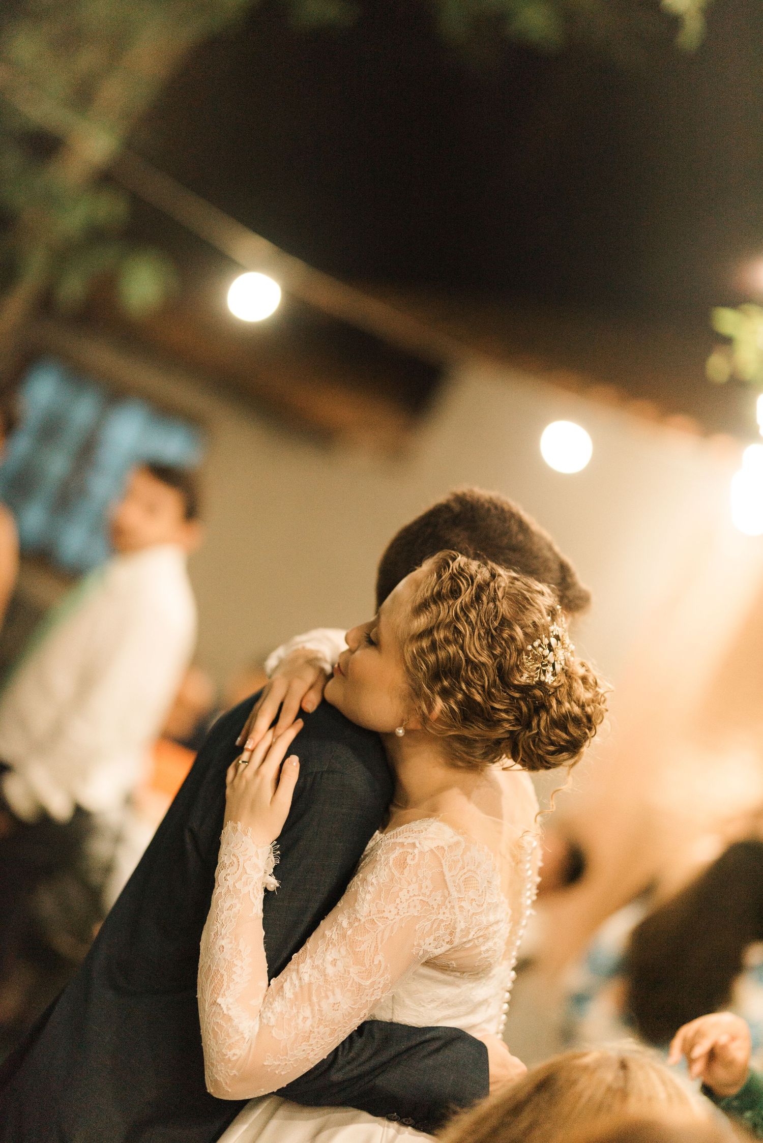 A couple share an intimate dance moment at their wedding reception under soft lighting.