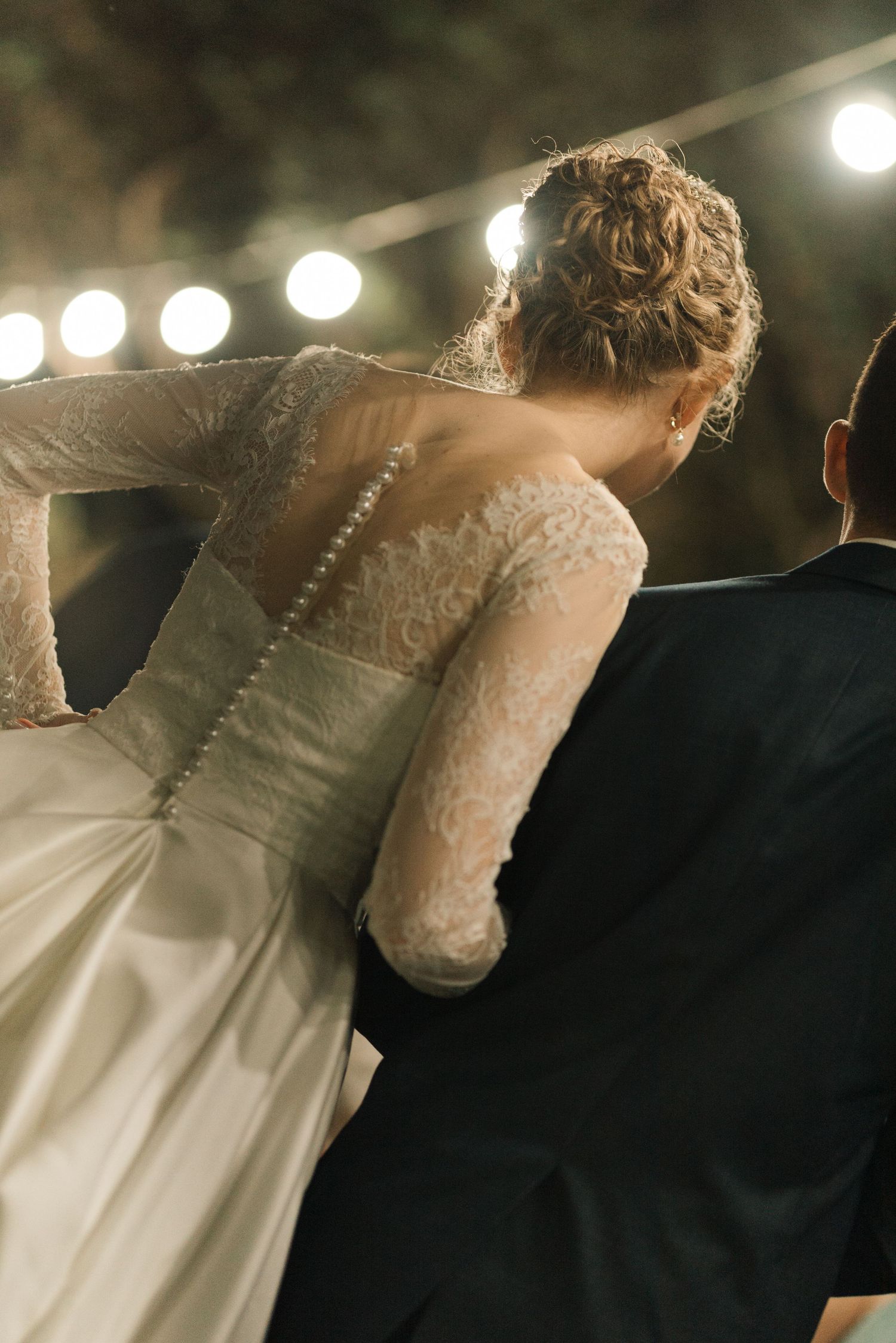 The detailed back of a wedding gown with delicate lace sleeves and button details.