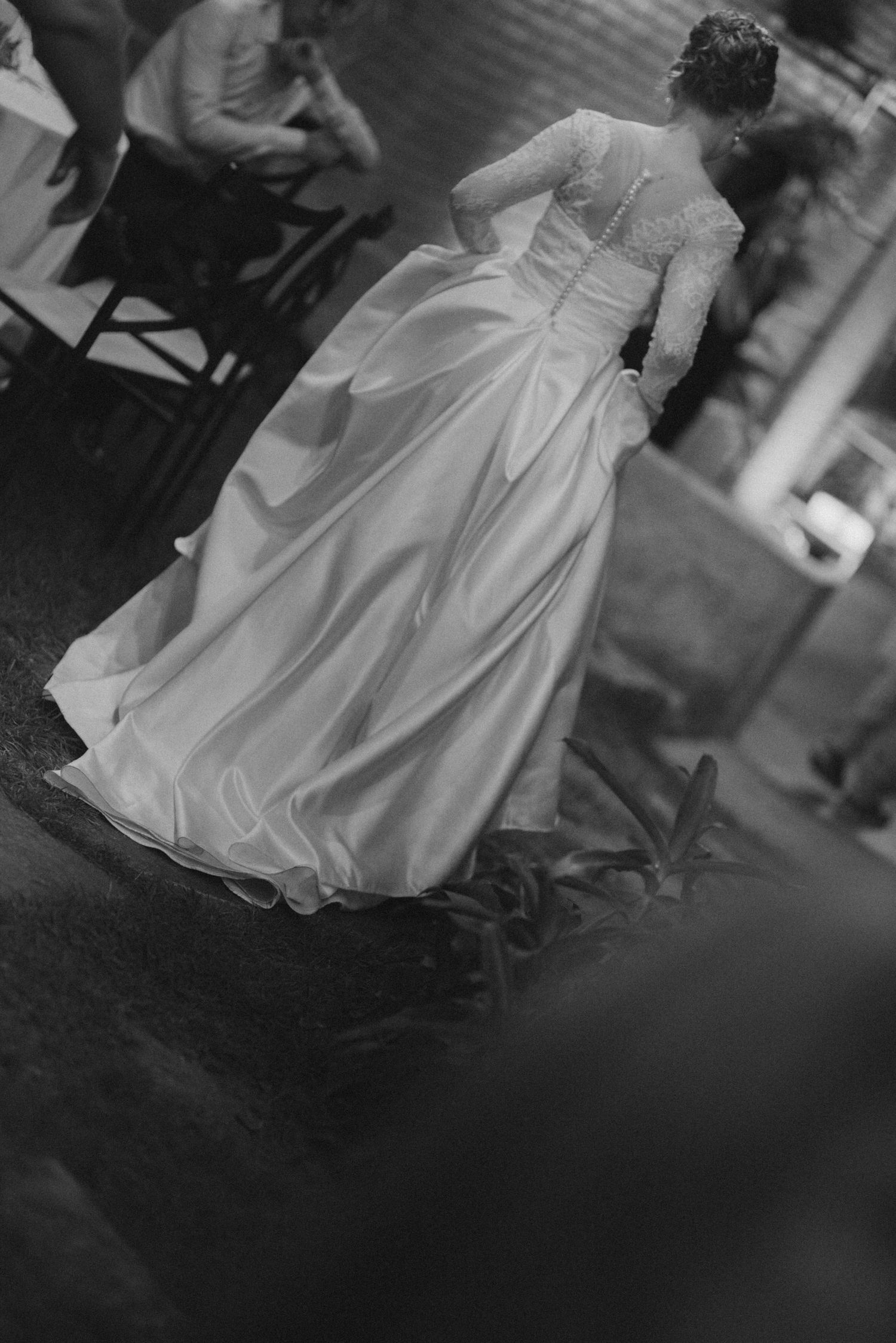A black and white photo showing the elegant flow of a wedding dress during a reception.