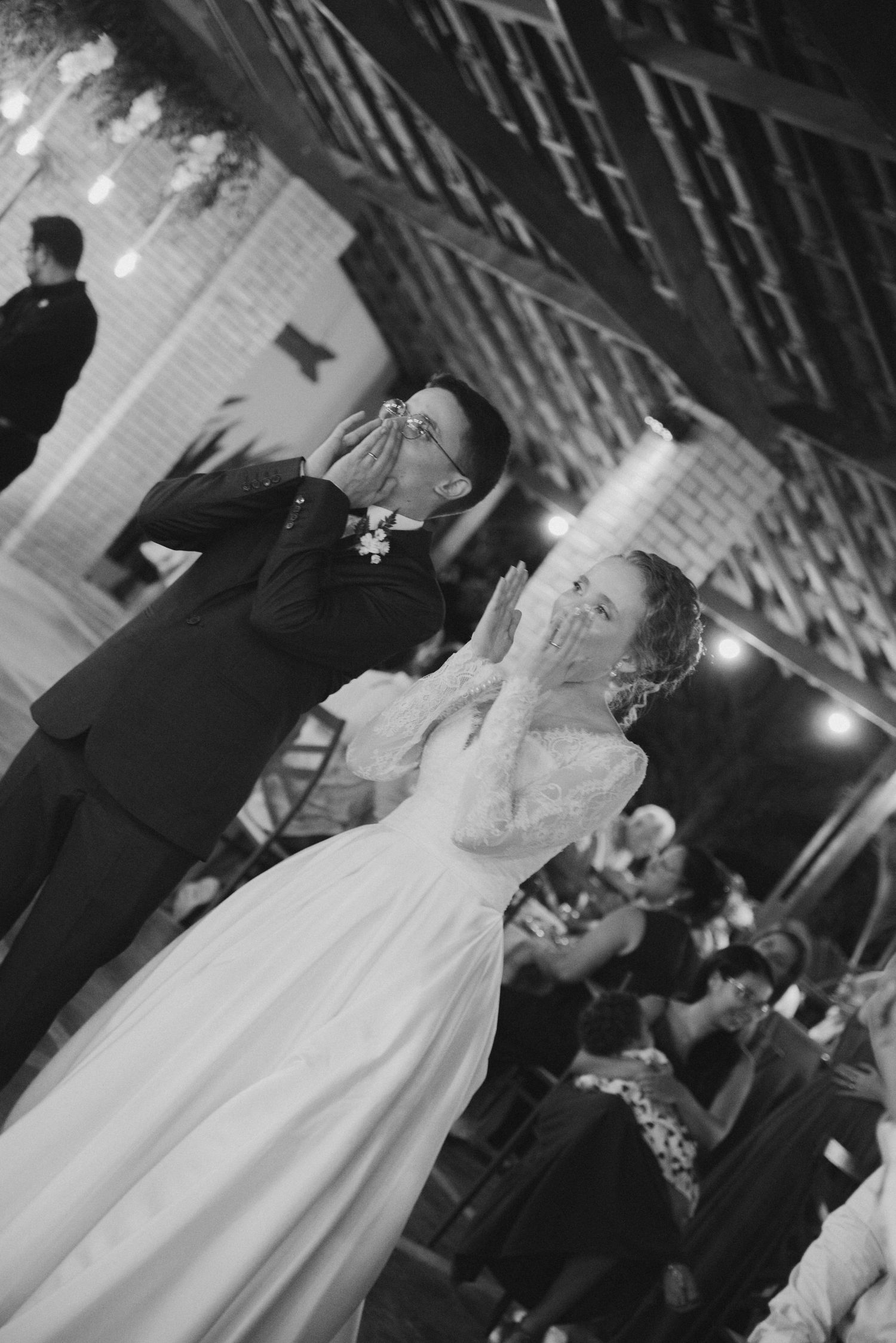A playful wedding reception moment captured in black and white photography.