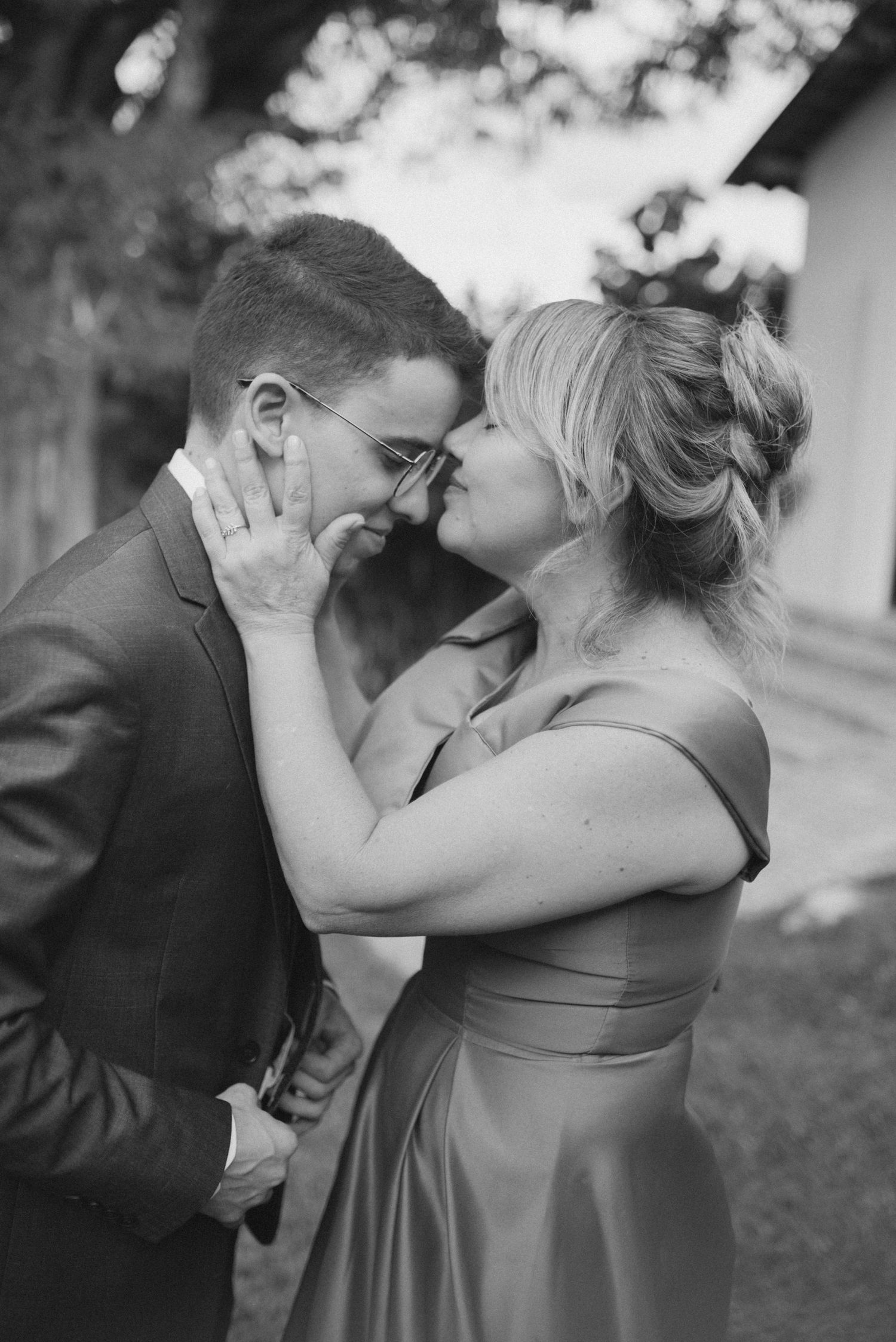 Intimate black and white portrait of couple sharing tender moment outdoors.