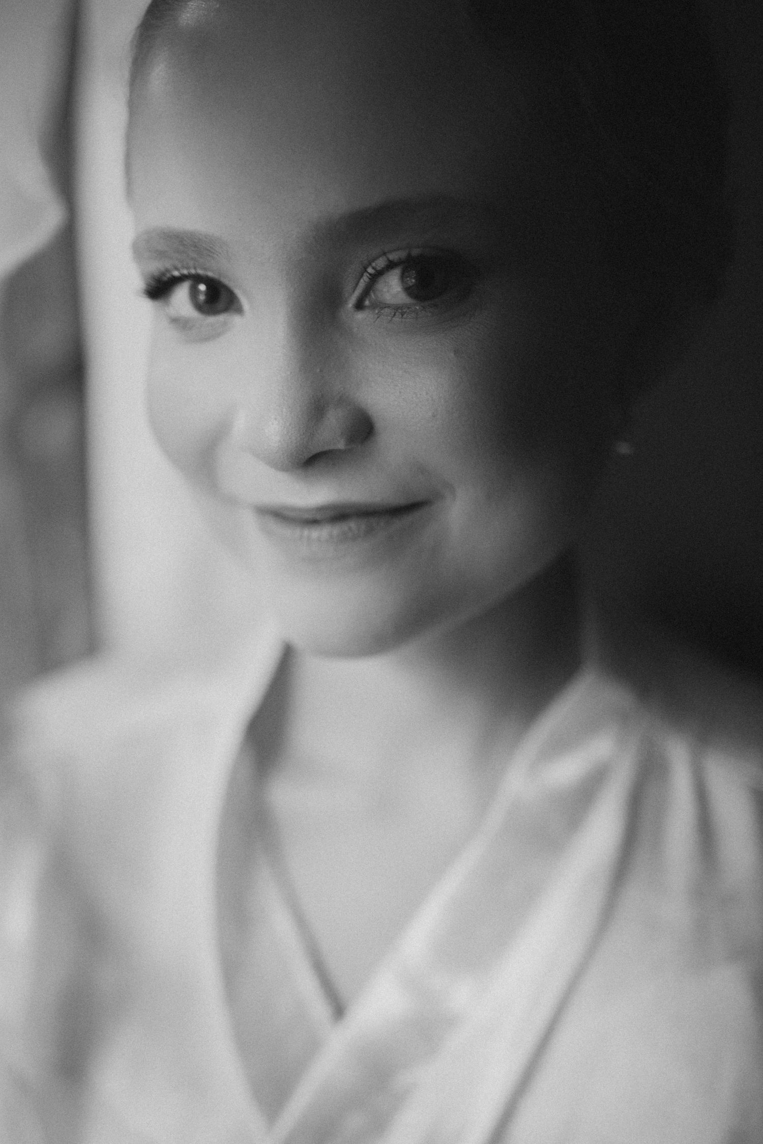 Black and white close-up portrait with gentle expression in white robe.
