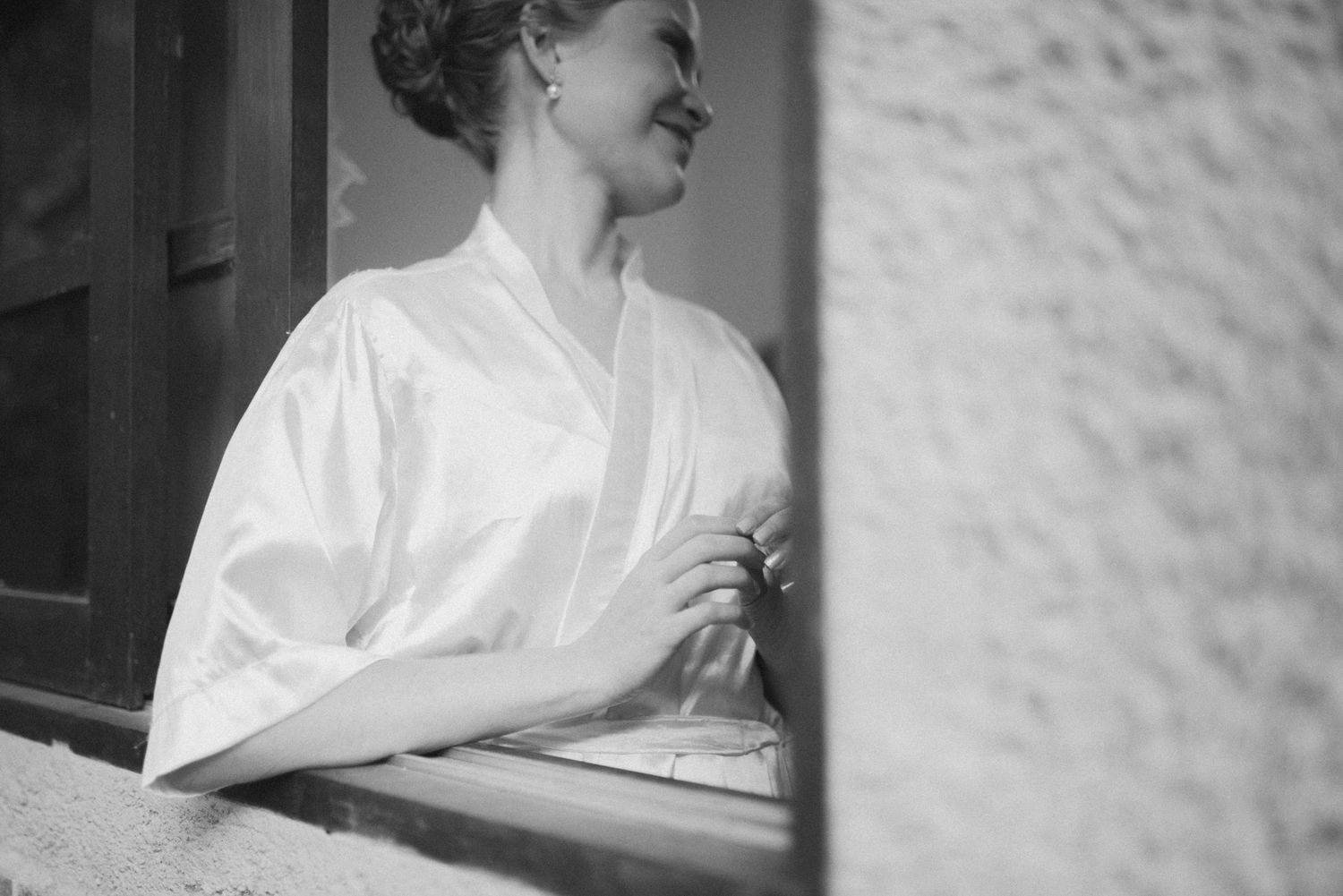 Black and white candid portrait showing genuine laughter by window.