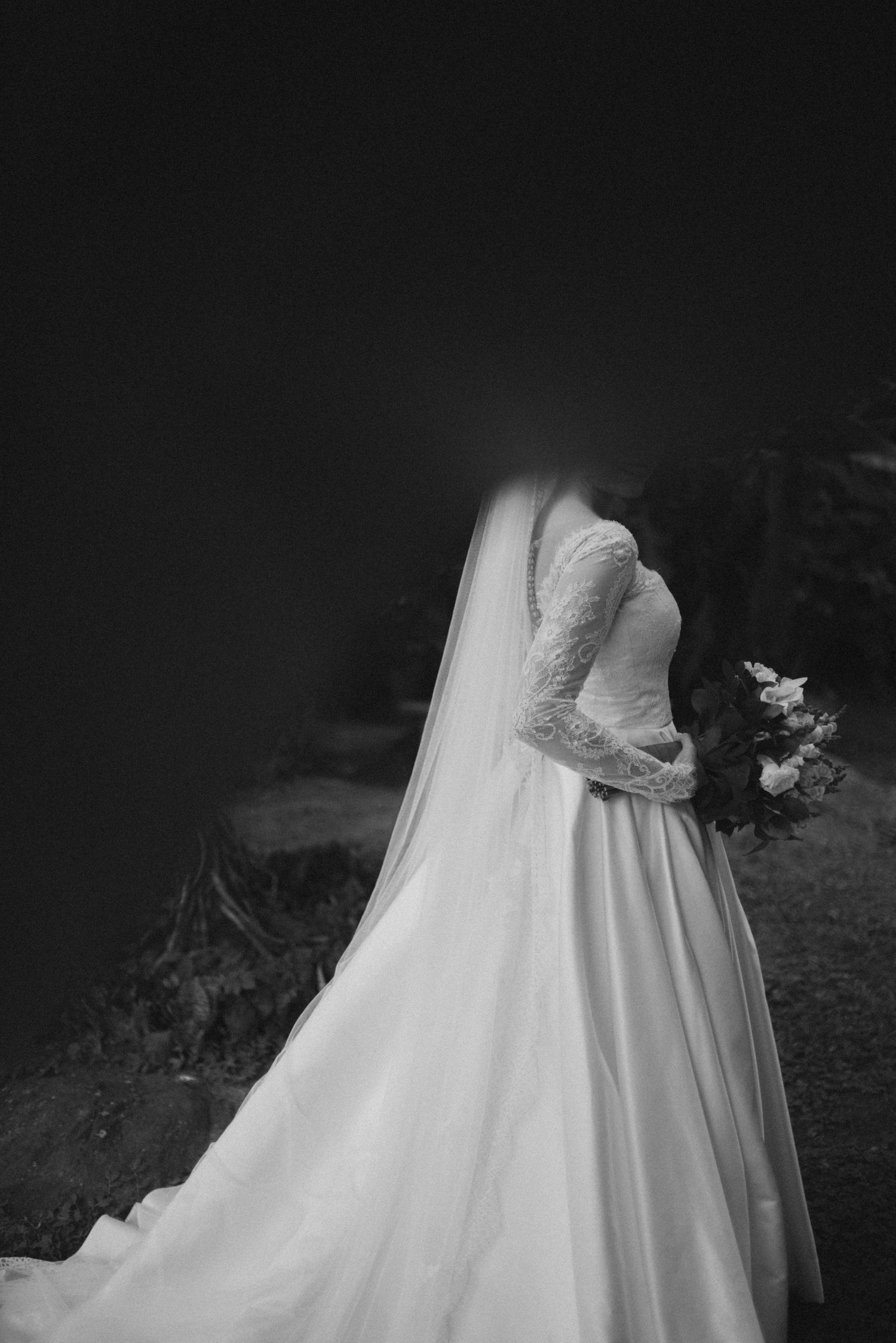 Back view of an elegant white wedding dress with lace details and flowing veil.