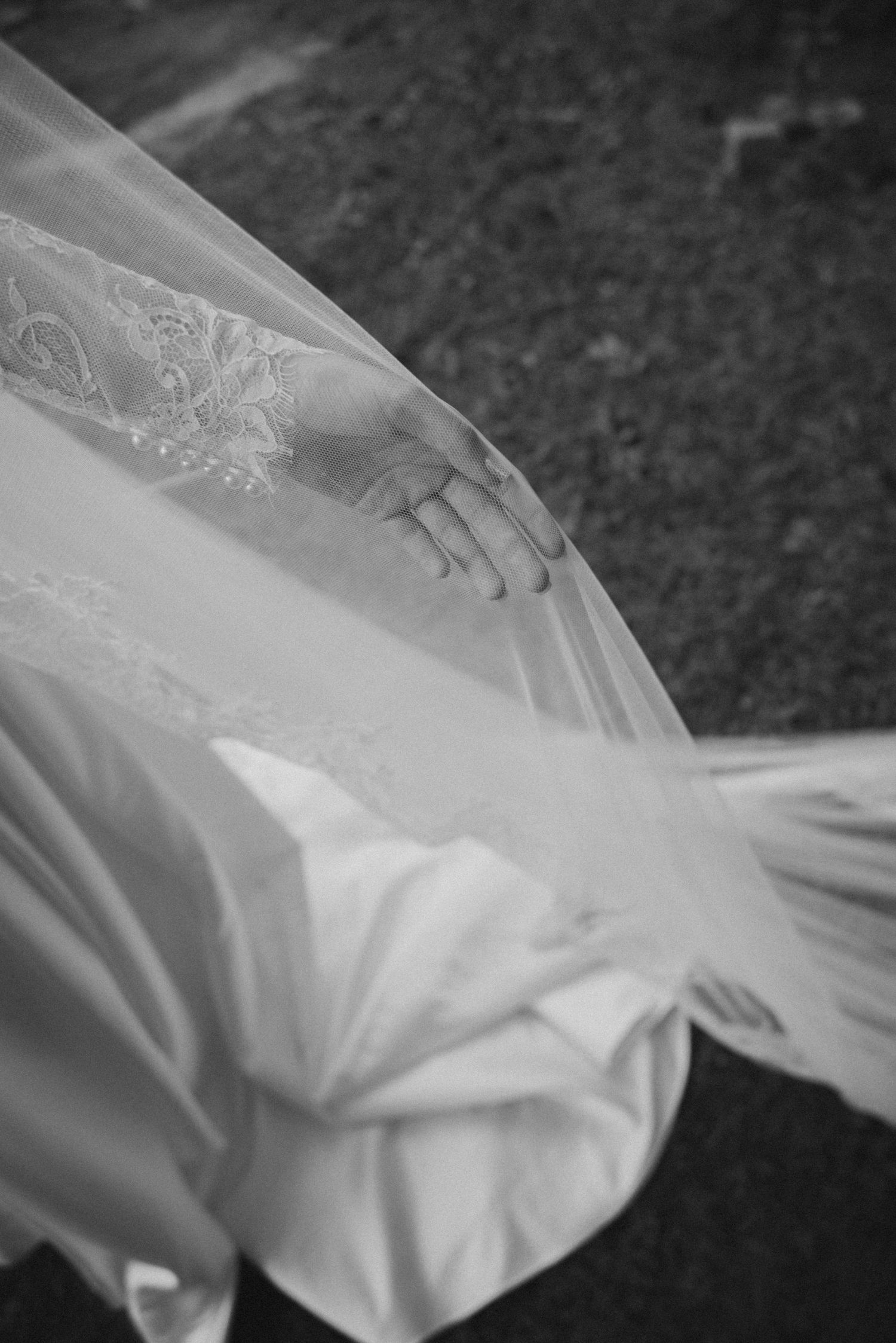 Close-up black and white detail of delicate lace and tulle wedding dress fabric.