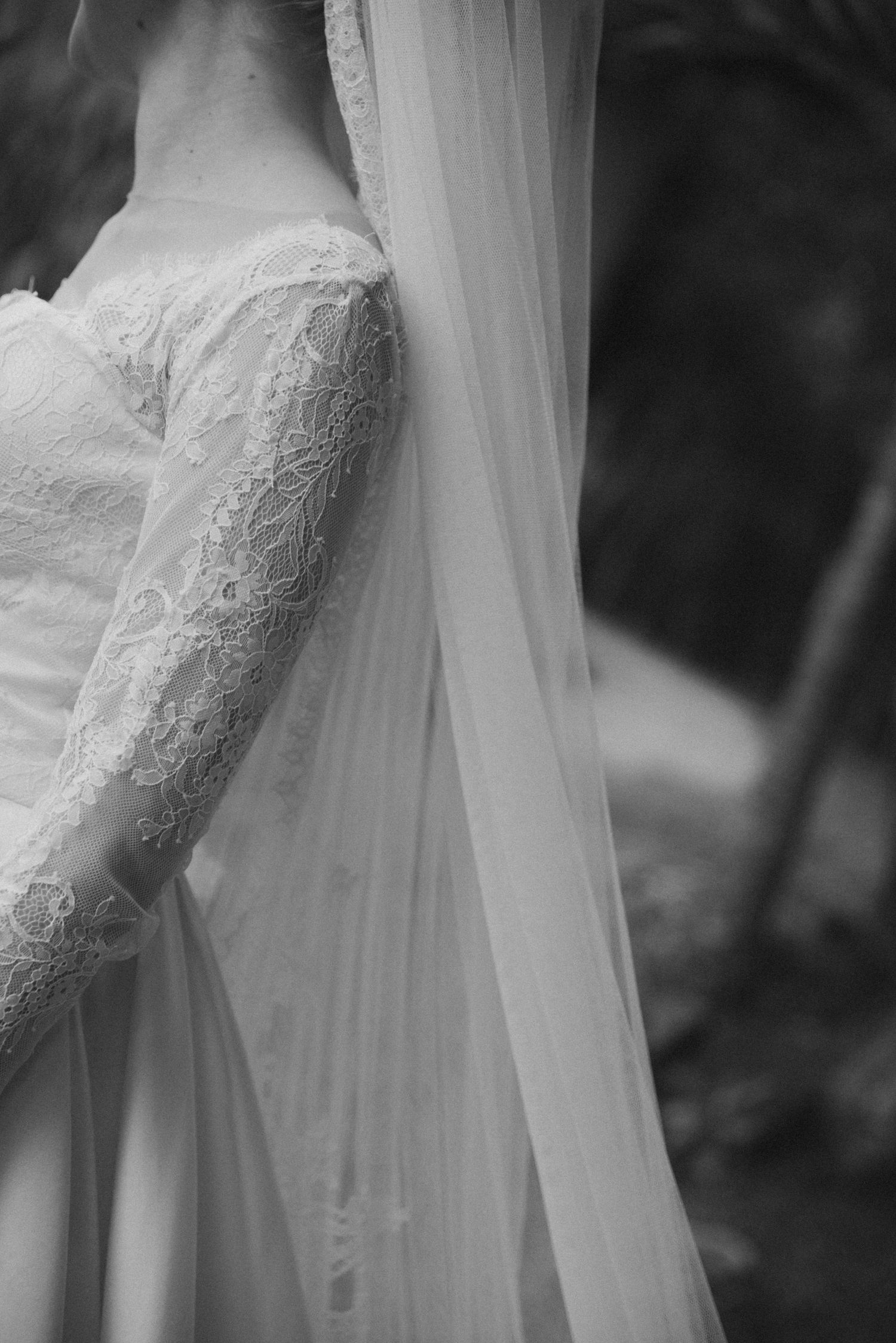 Detailed black and white shot of lace wedding dress bodice with flowing veil.