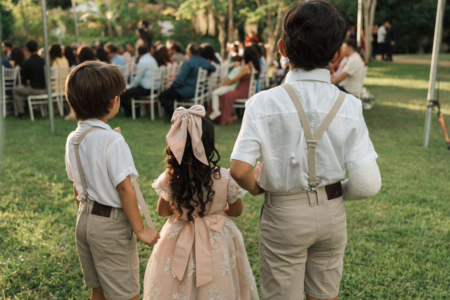 Wedding attendants in matching outfits stand together during an outdoor ceremony.