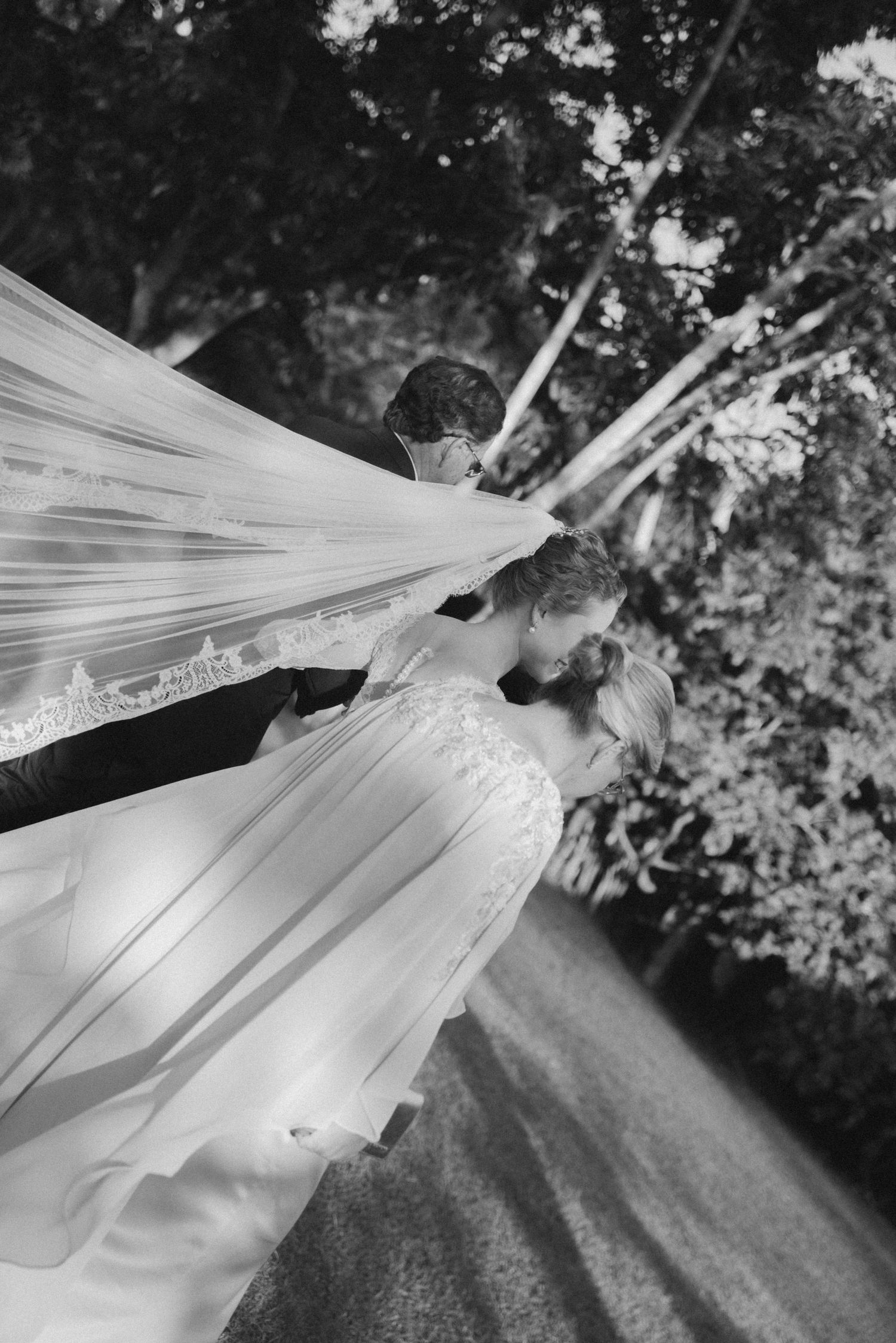 Black and white image of a flowing wedding veil caught in dramatic motion outdoors.