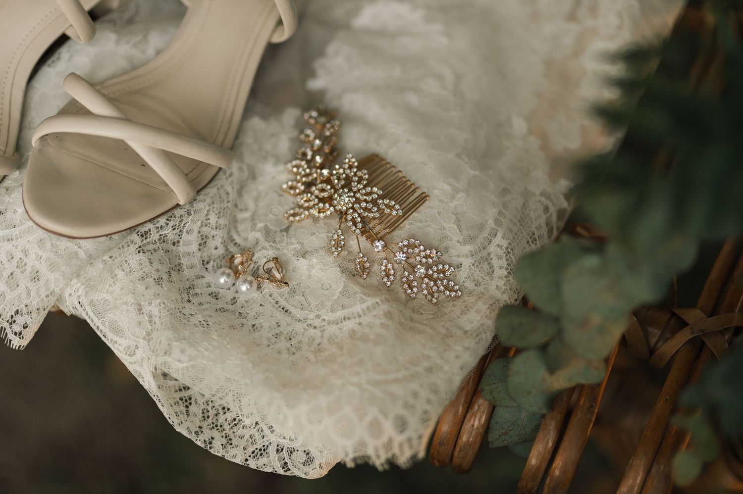 Close-up detail of beaded lace embellishments on wedding dress with bridal shoe.