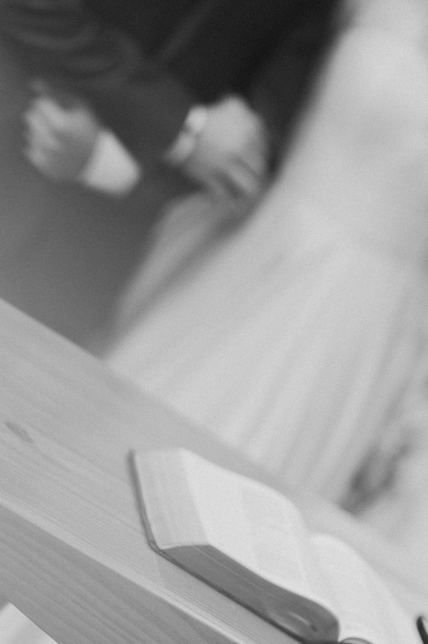 A close-up black and white photo of an open Bible on a wooden table during a wedding ceremony.