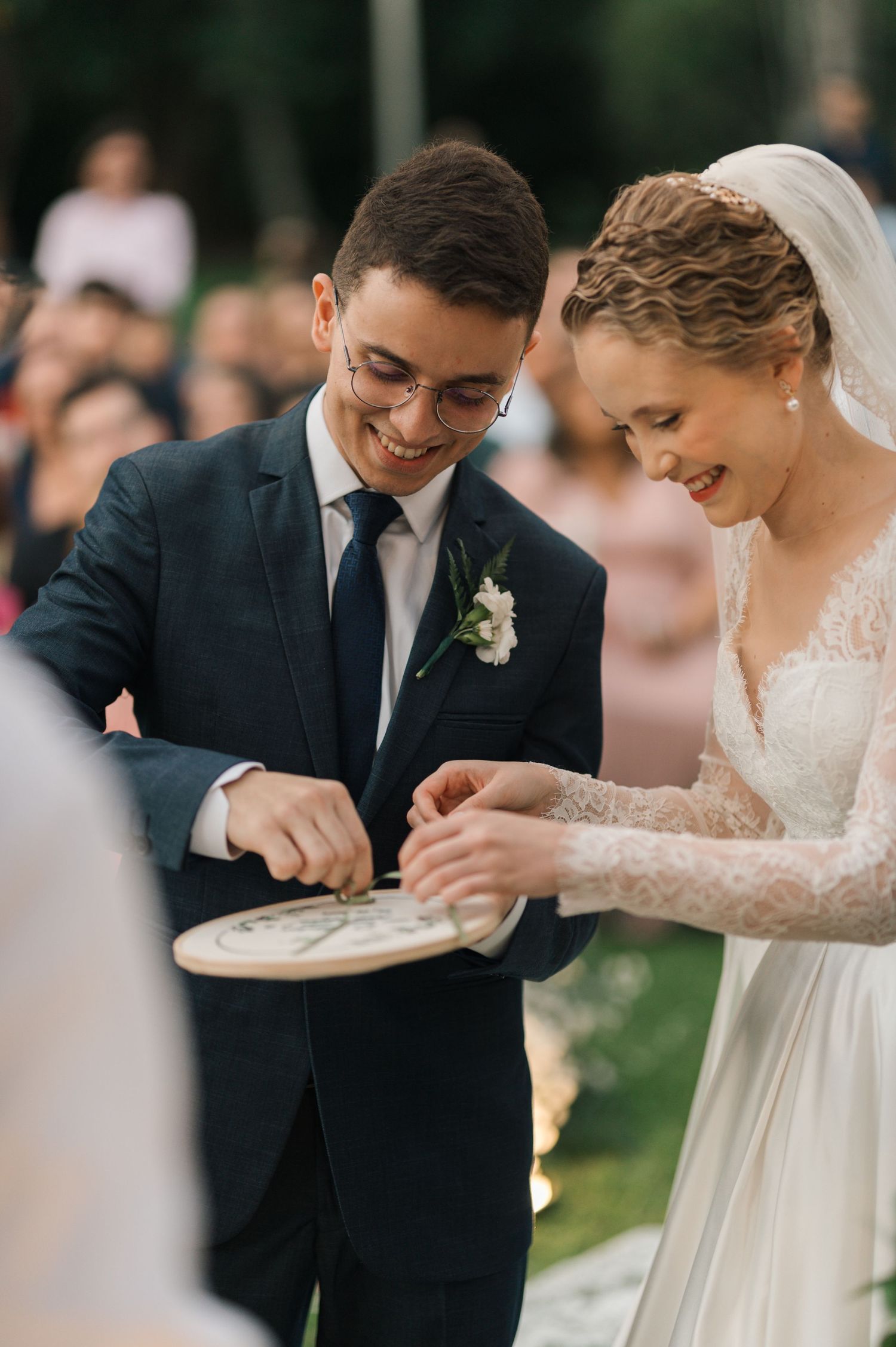 Newlyweds share a sweet moment during their ring exchange at an outdoor garden ceremony.