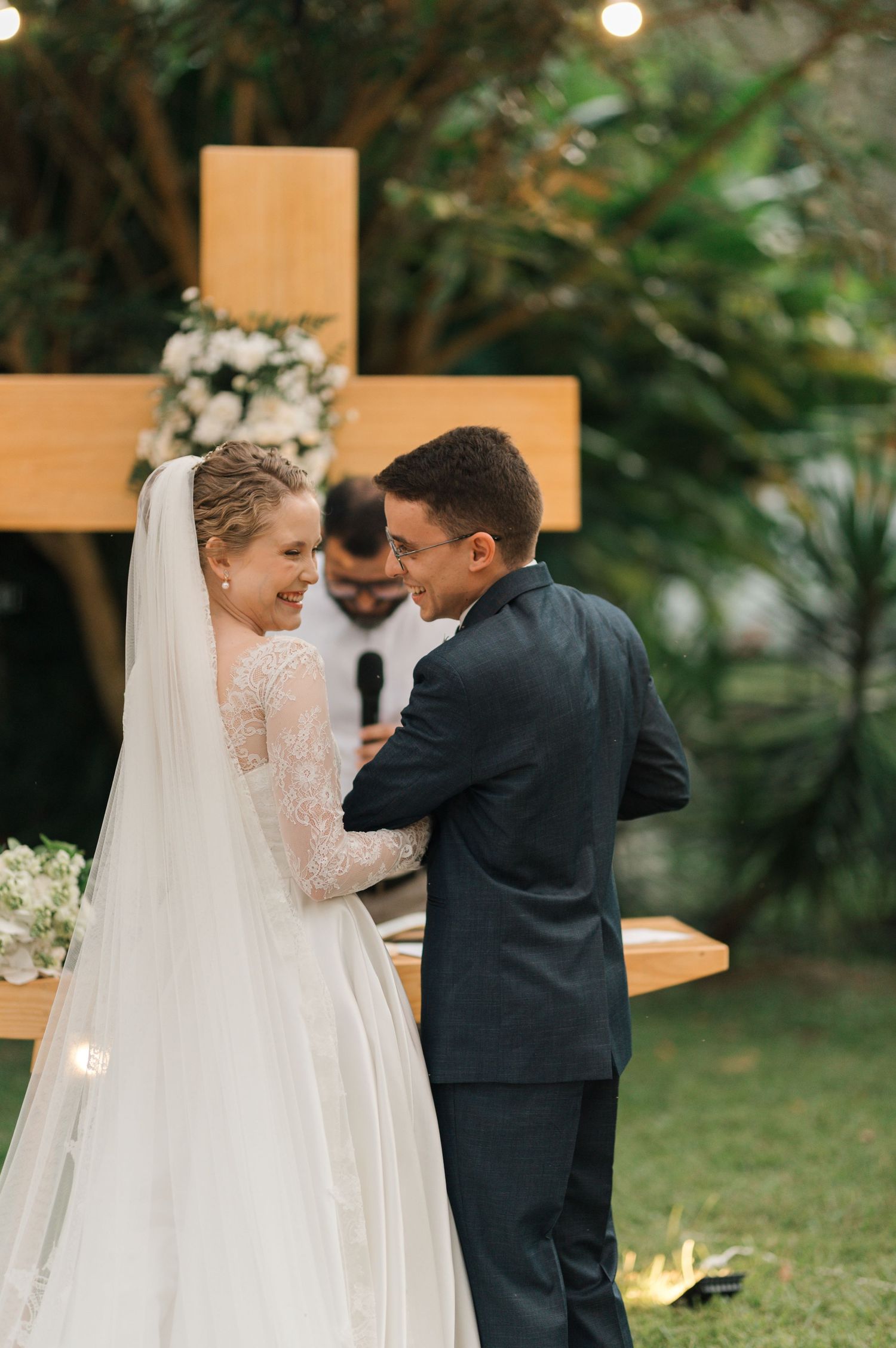 Couple celebrates during their garden wedding ceremony with a decorative wooden cross backdrop.