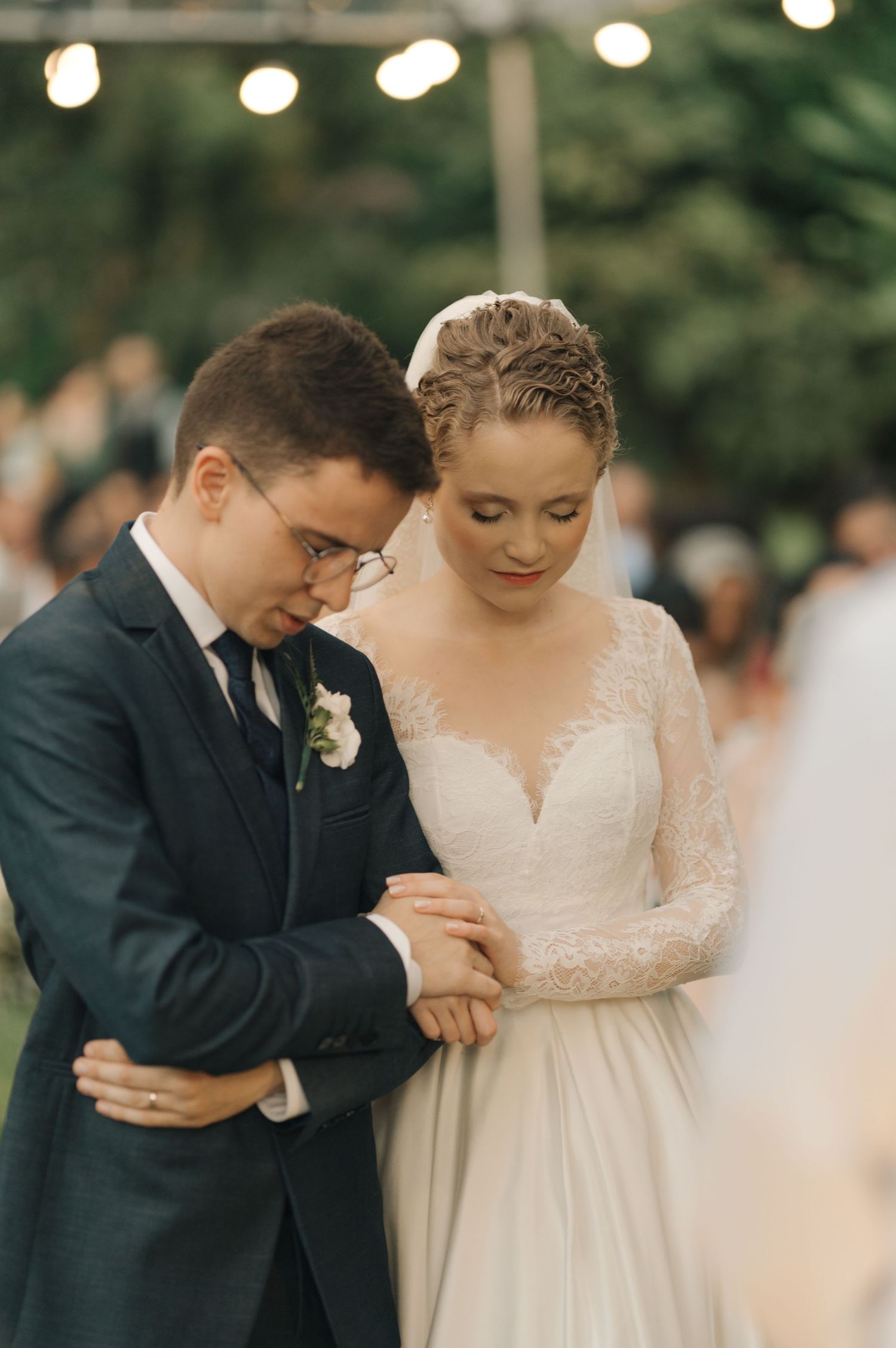 Couple shares an intimate moment during their wedding ceremony under string lights.