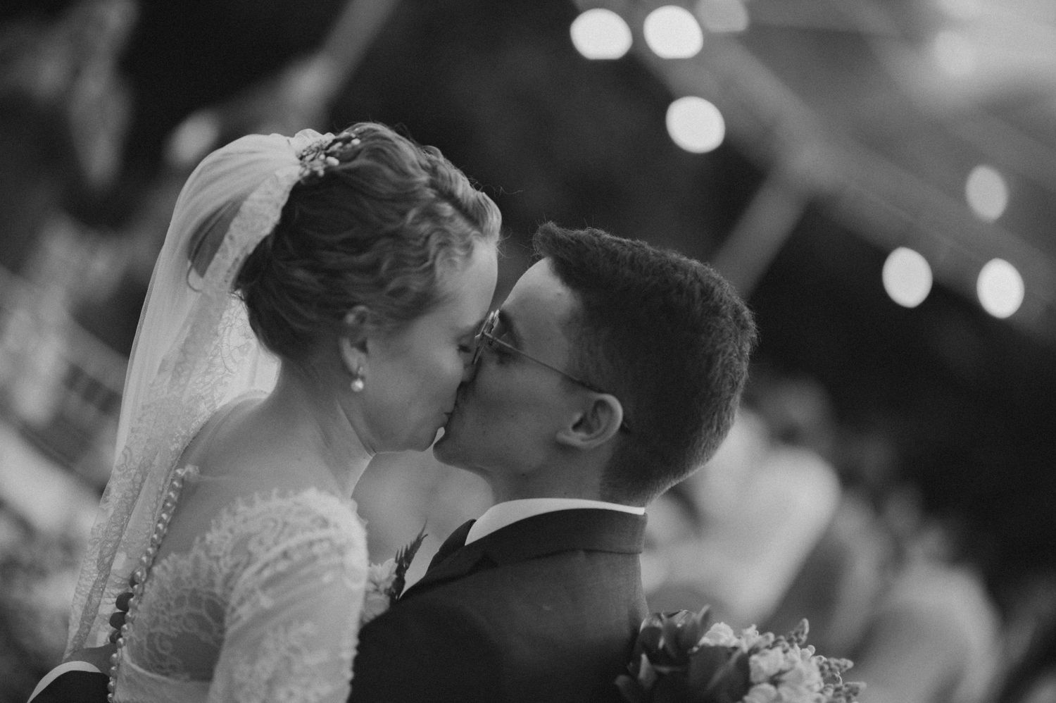 A romantic black and white capture of newlyweds sharing their first kiss.