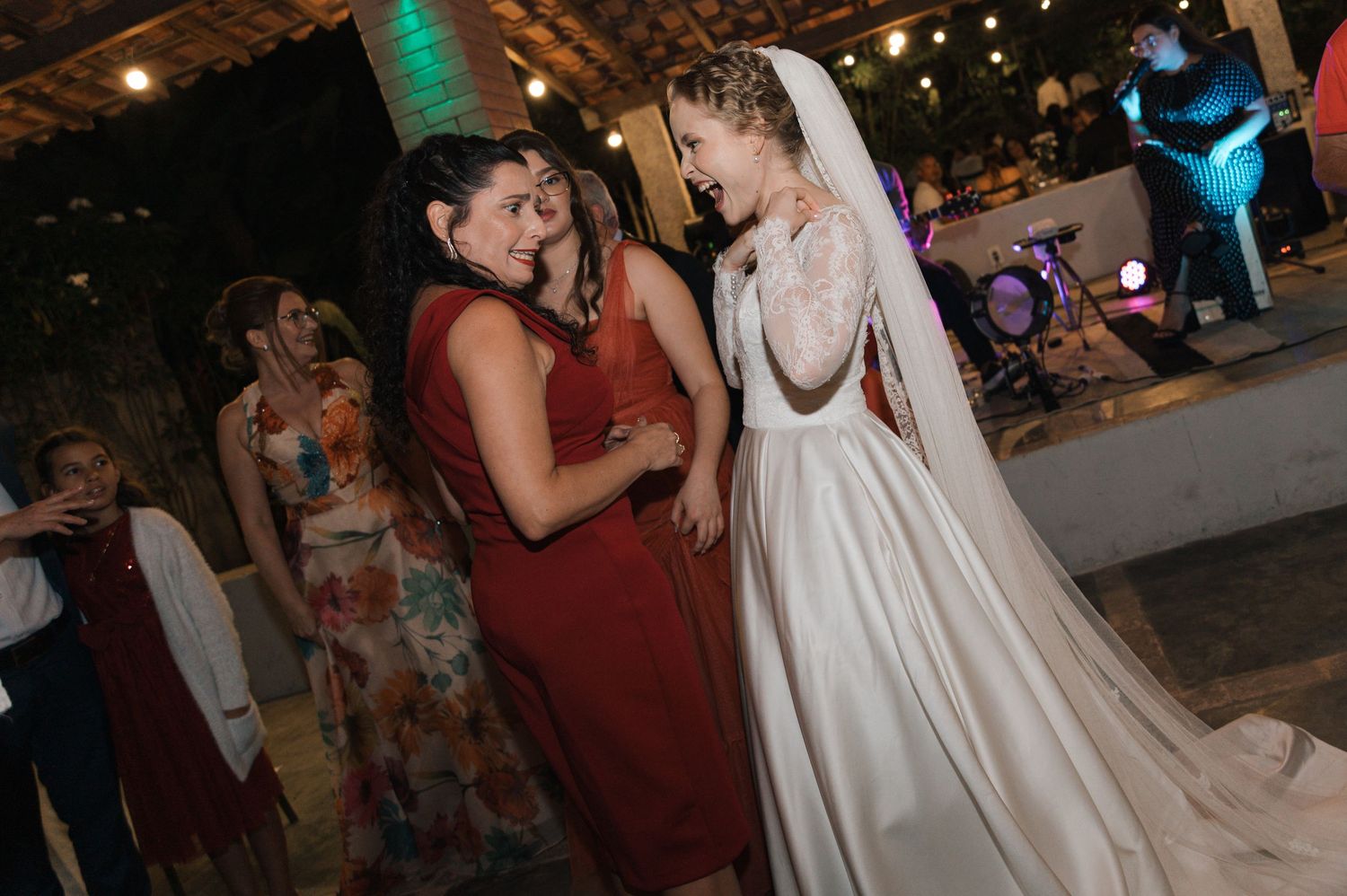 Wedding reception candid moment showing guests and the bride laughing during evening celebrations.