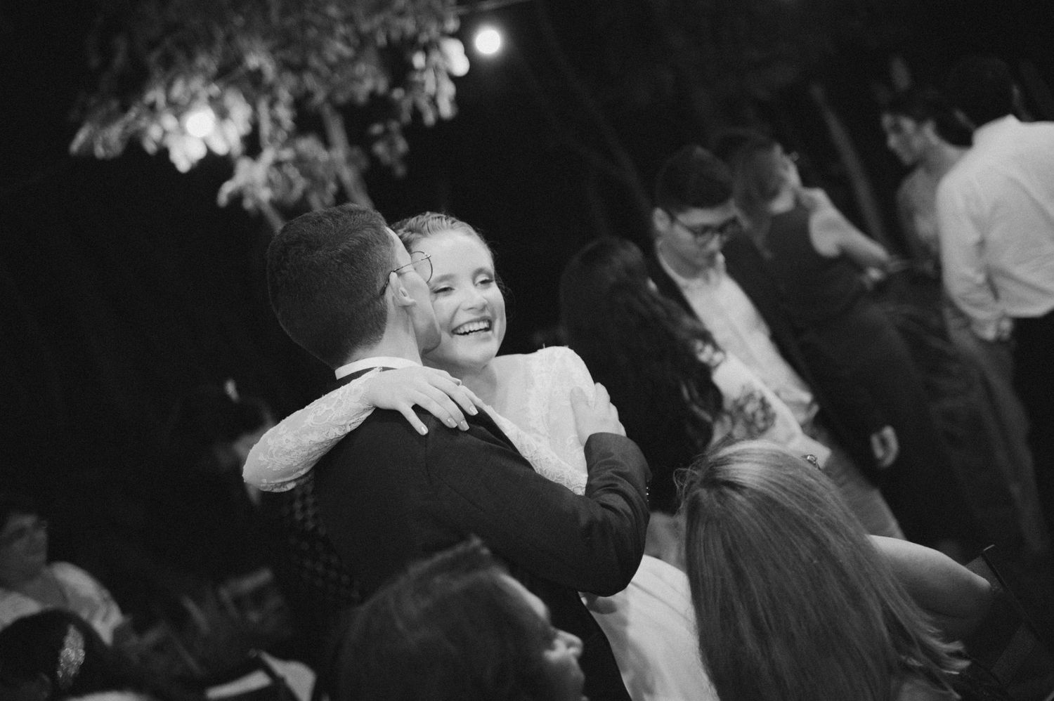 Guests enjoying a joyful moment on the dance floor at a wedding reception under dim lighting.
