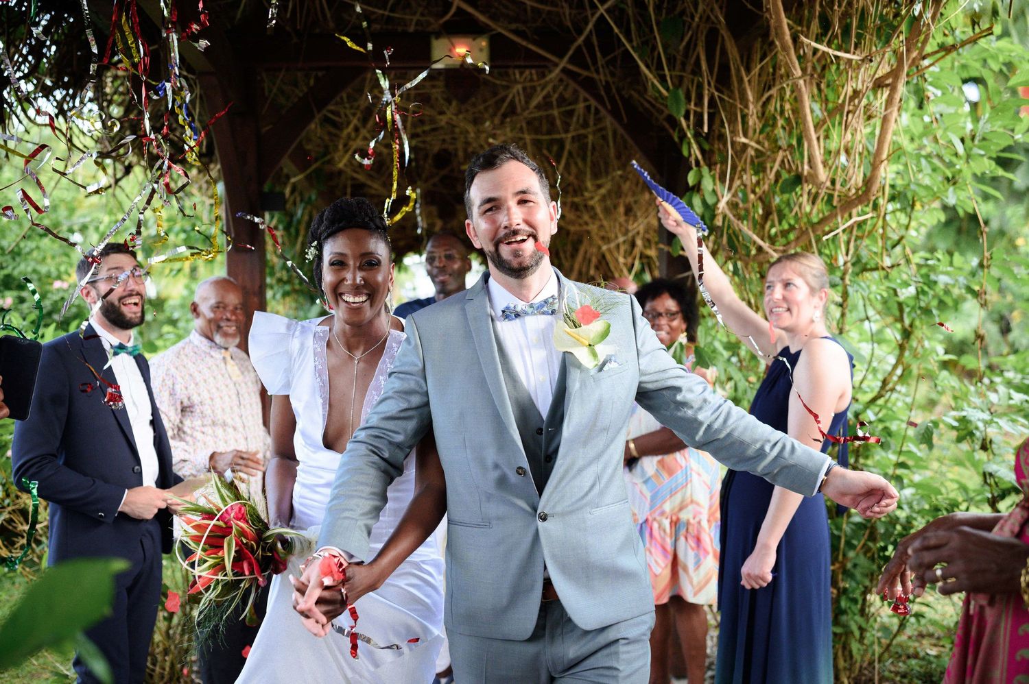 Couple de mariés en Martinique joyeux avec des confettis lancés par les invités en Martinique