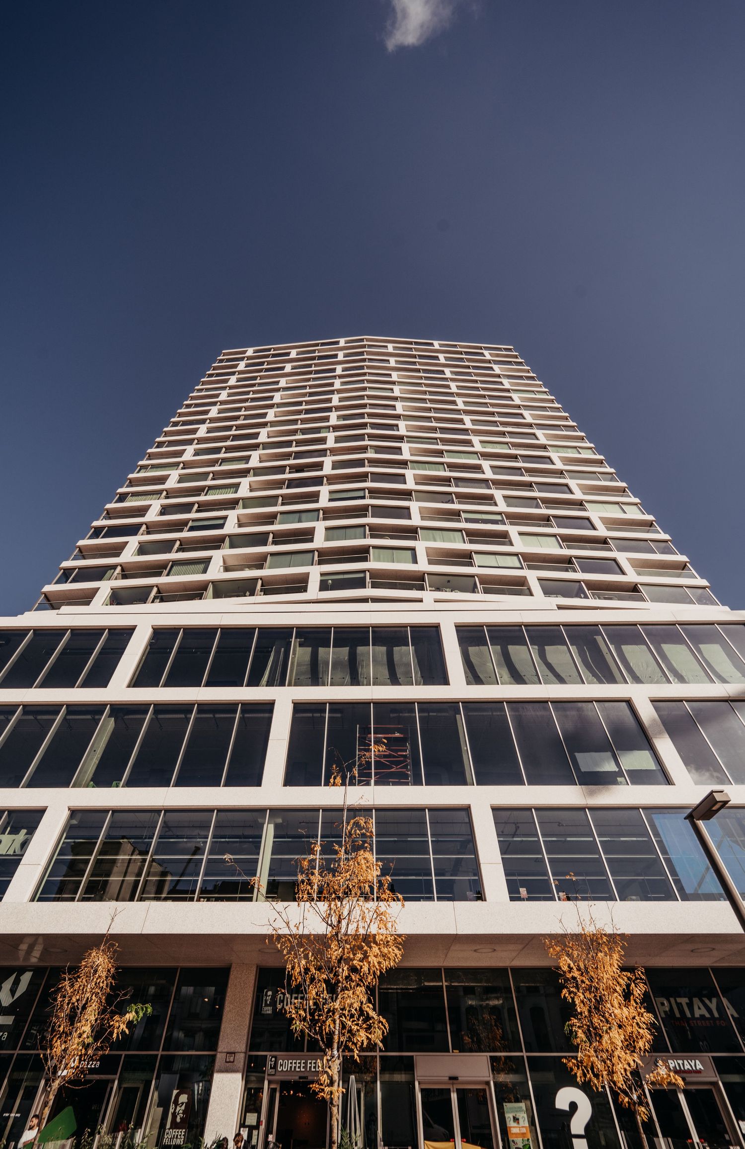 Moderne hoogbouw met kenmerkend geometrisch patroon en glazen ramen tegen blauwe lucht.