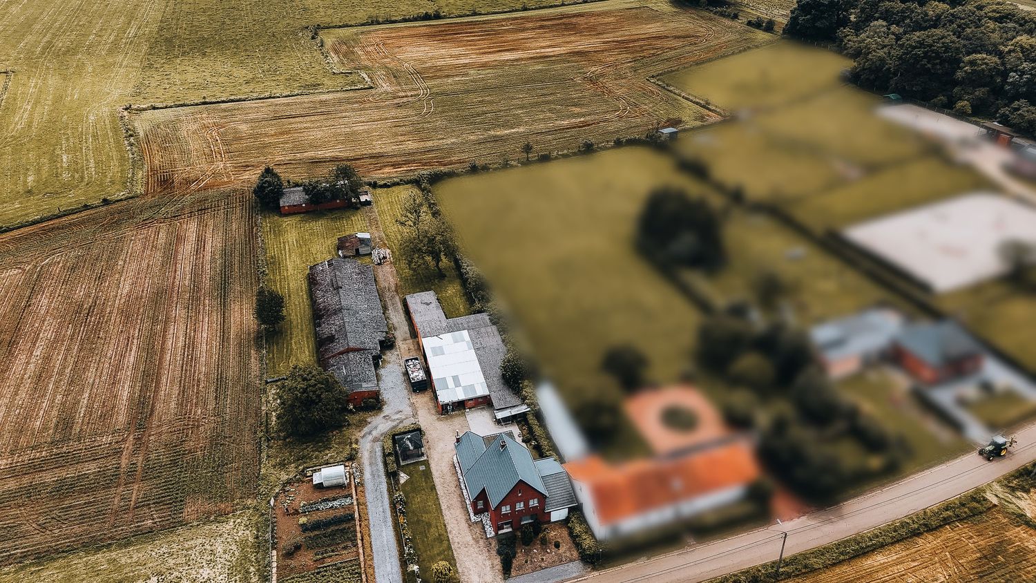 Drone-perspectief van boerderijgebouwen en een cirkelvormige binnenplaats tussen de landbouwvelden.