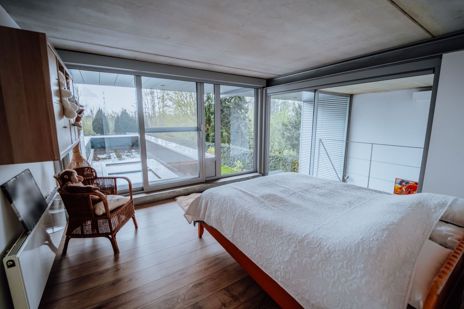 Lichte slaapkamer met grote ramen, houten vloeren en moderne meubels met uitzicht op het buitenlandschap.