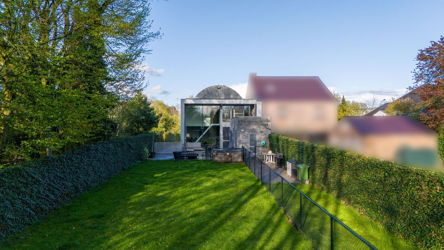 Groot huis met verzorgd gazon en hoge heggen rondom het pand.