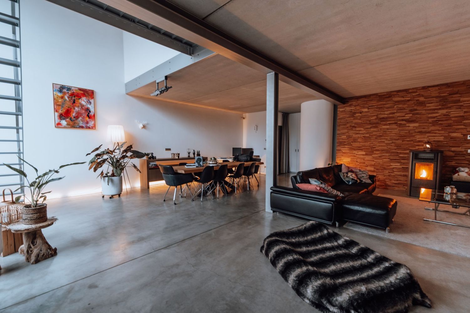 Moderne loft woonkamer met betonnen vloeren, zichtbare bakstenen muur en minimalistisch meubelontwerp.
