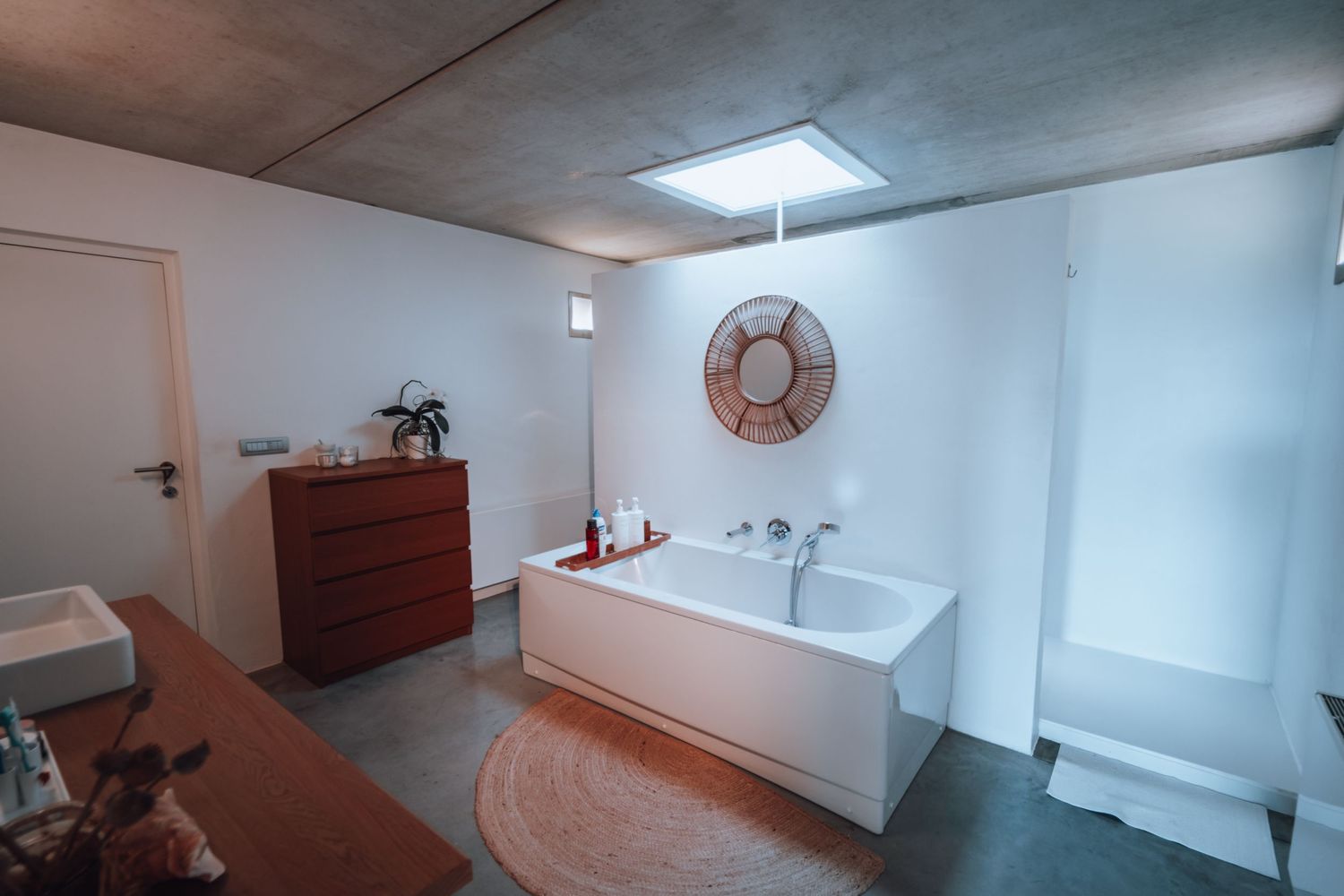 Moderne badkamer met een vrijstaand bad, ronde wandspiegel en minimalistische designelementen.